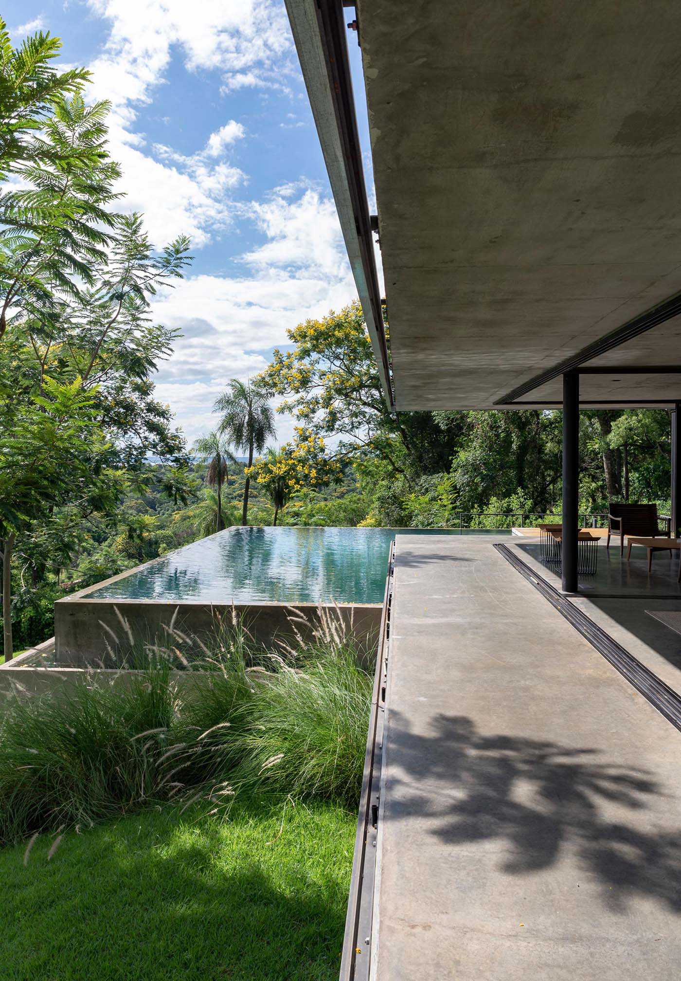 A modern house that has an infinity edge swimming pool that wraps around the corner.
