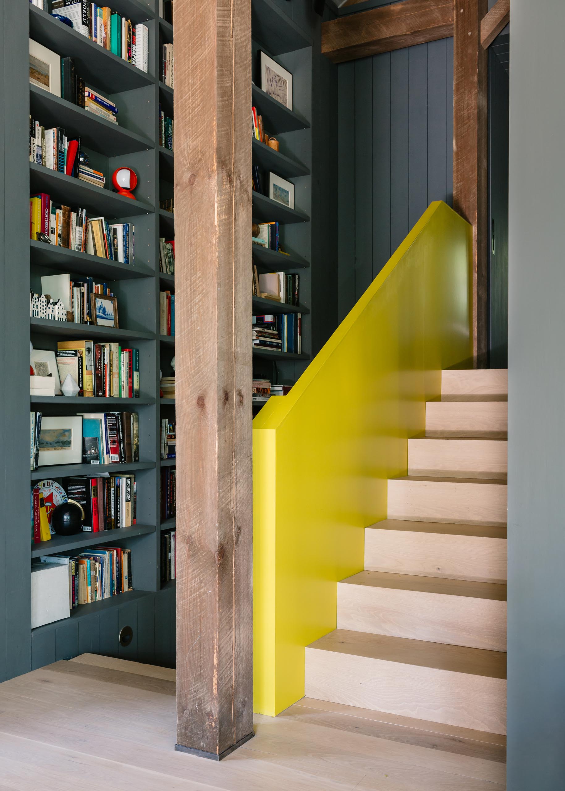 A barn-inspired home with custom bookshelves and a yellow handrail accent.