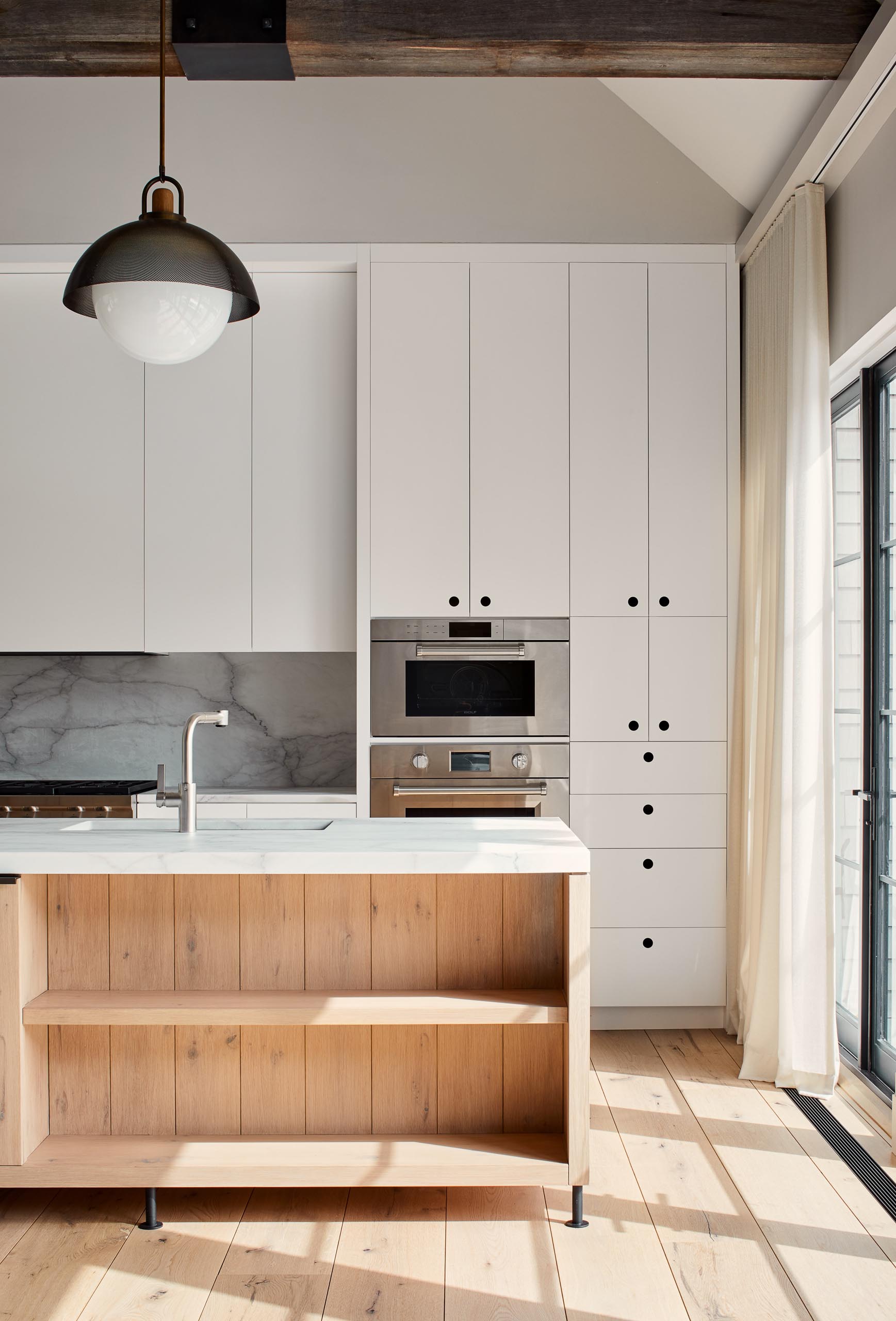 The cabinets in this kitchen are hardware free and include round recessed finger pulls that have been painted black inside.