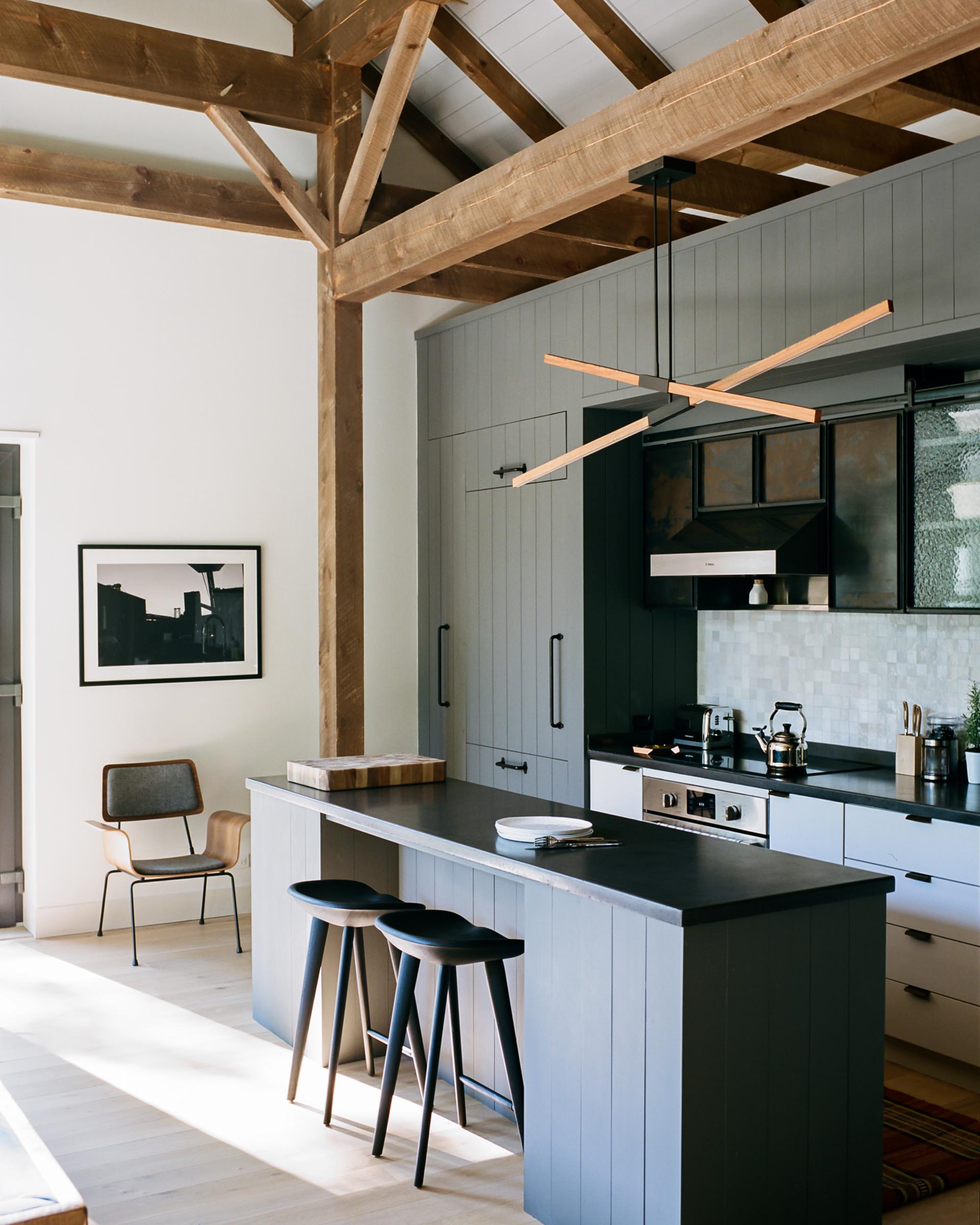 A modern gray kitchen with integrated fridge, dark countertops, and island.