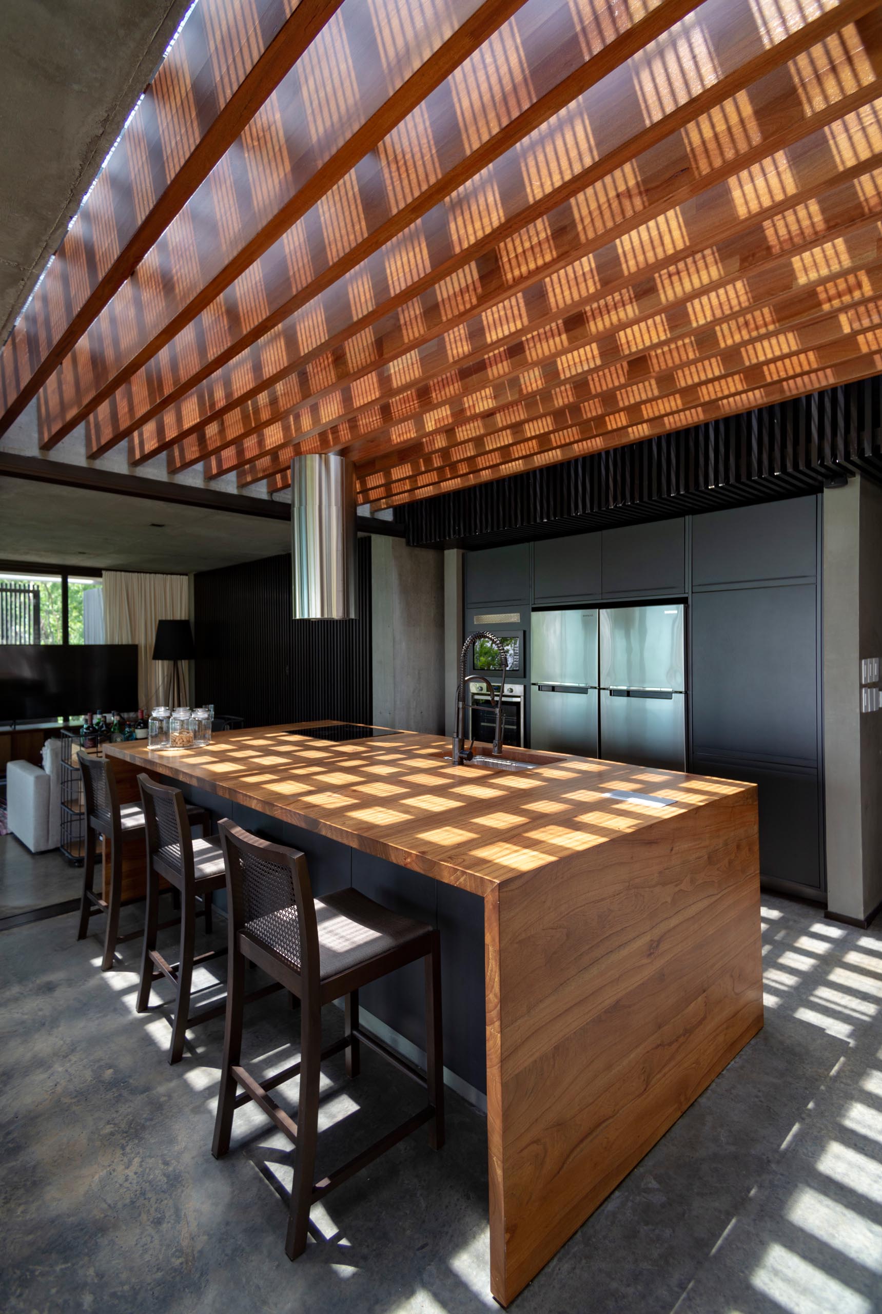 A modern kitchen with minimalist black cabinets and an oversized wood island.