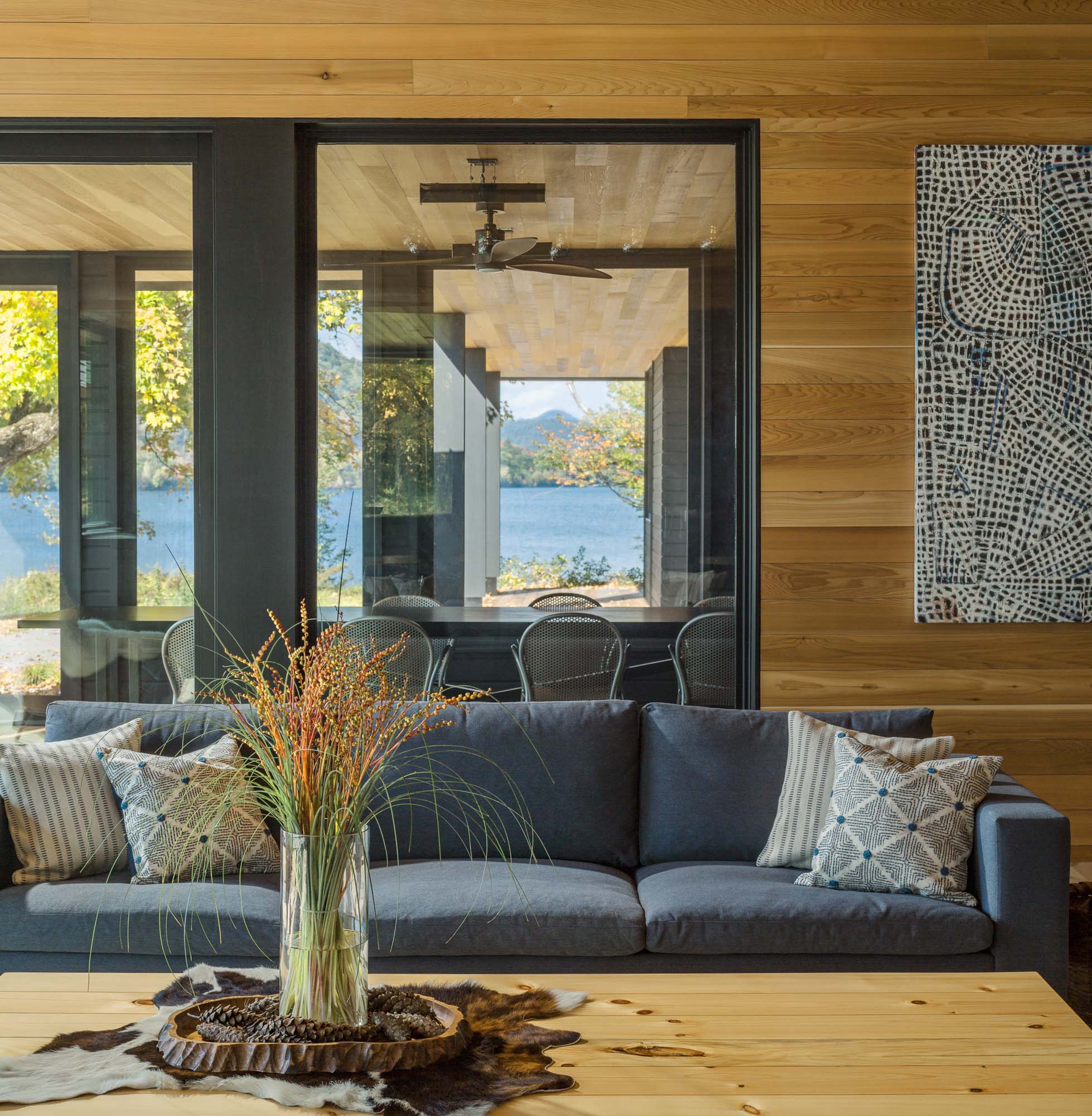 A modern lakeside home with a living room and nearby dining table.