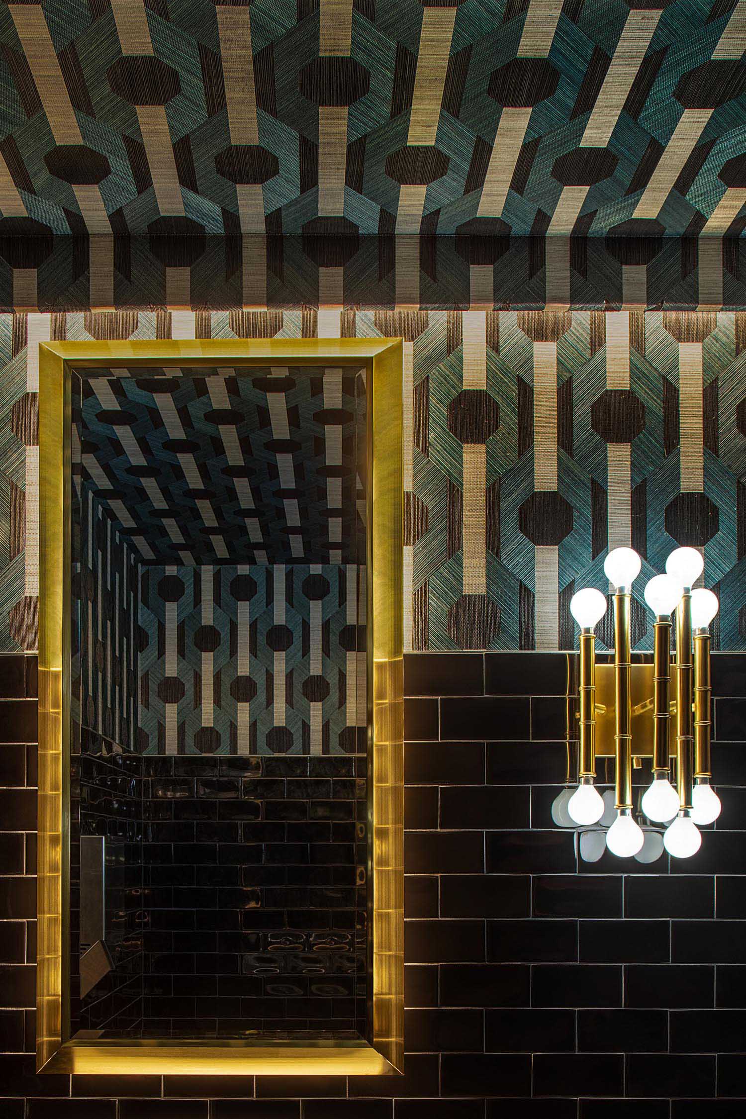 Patterned walls and black subway tiles in a restaurant bathroom.