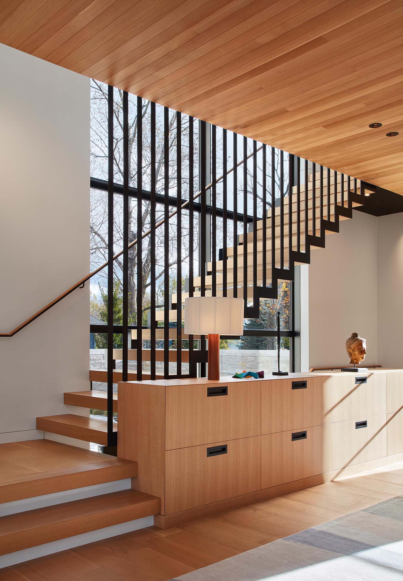 A suspended steel staircase with white oak treads connects the different levels of the home, while built-in cabinetry adds an element of storage.