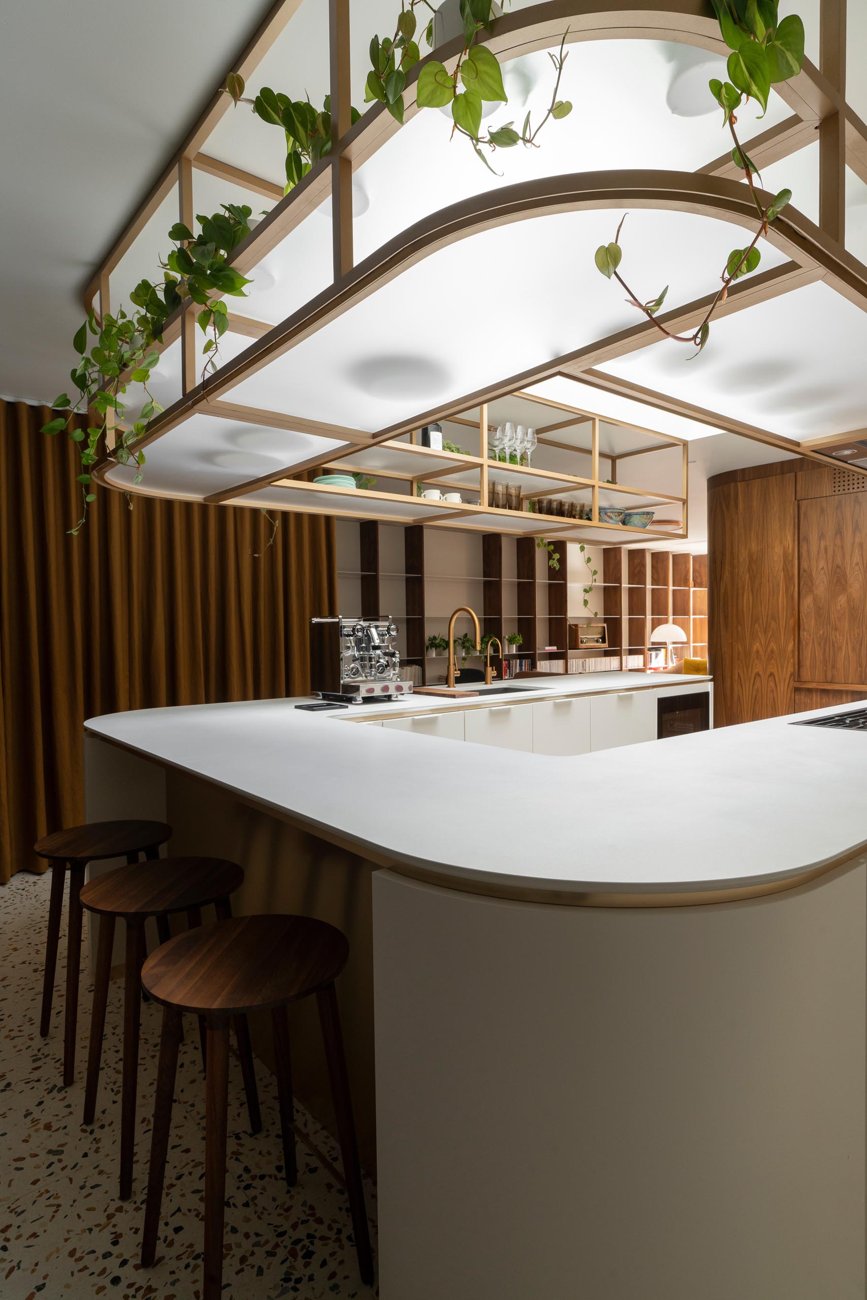 This modern U-shaped kitchen has a terrazzo tile floor, and an elegantly curved countertop with matching upper shelves that are open for easy access.  