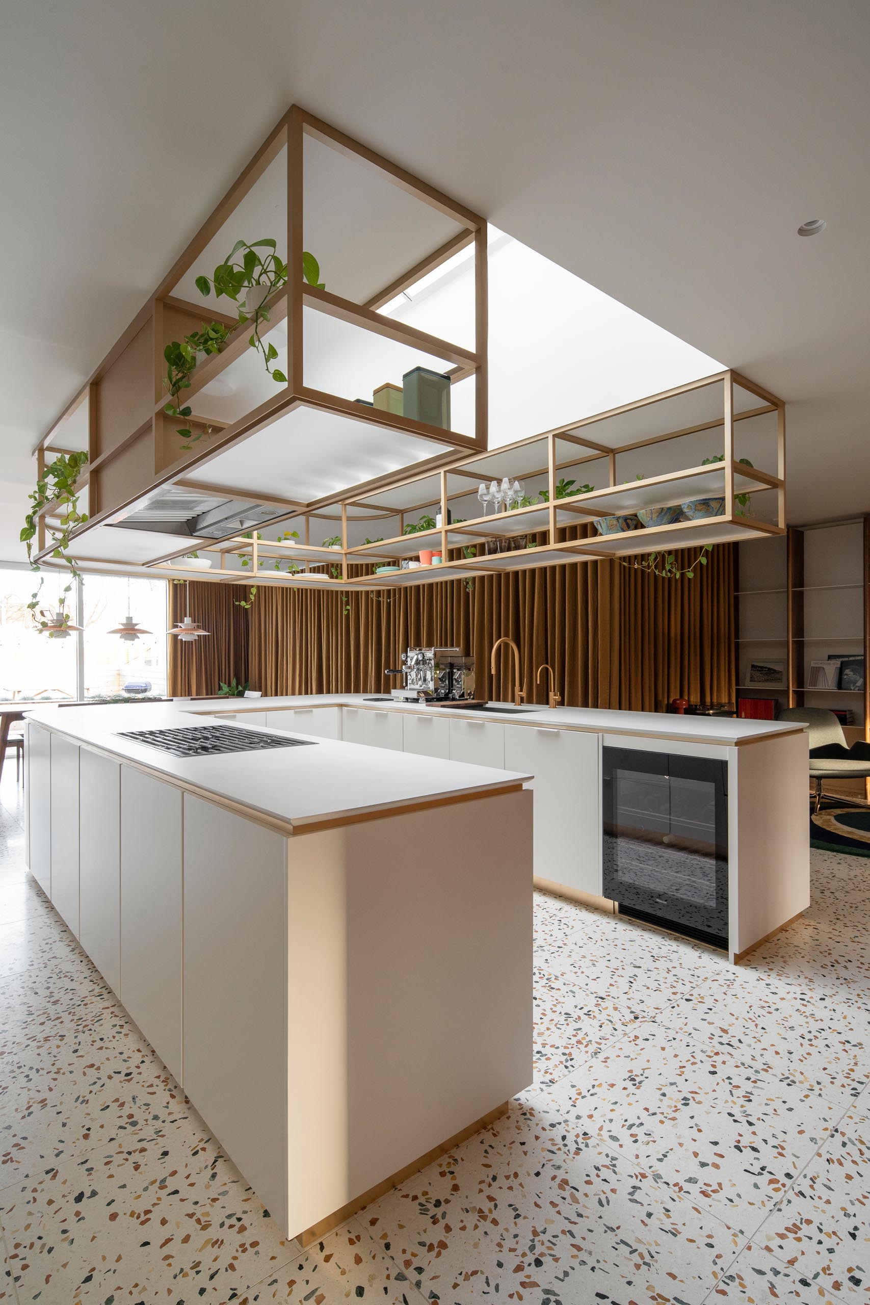 This modern U-shaped kitchen has a terrazzo tile floor, and an elegantly curved countertop with matching upper shelves that are open for easy access.
