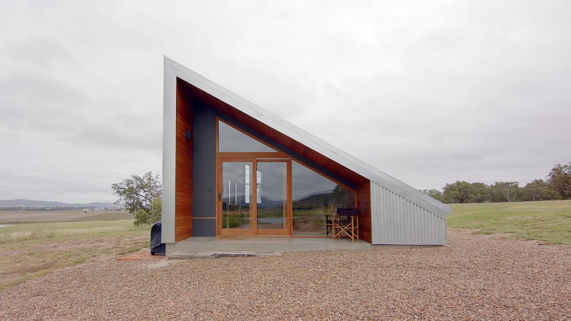 A modern off-grid tiny house with corrugated metal siding and wood framed windows and doors.