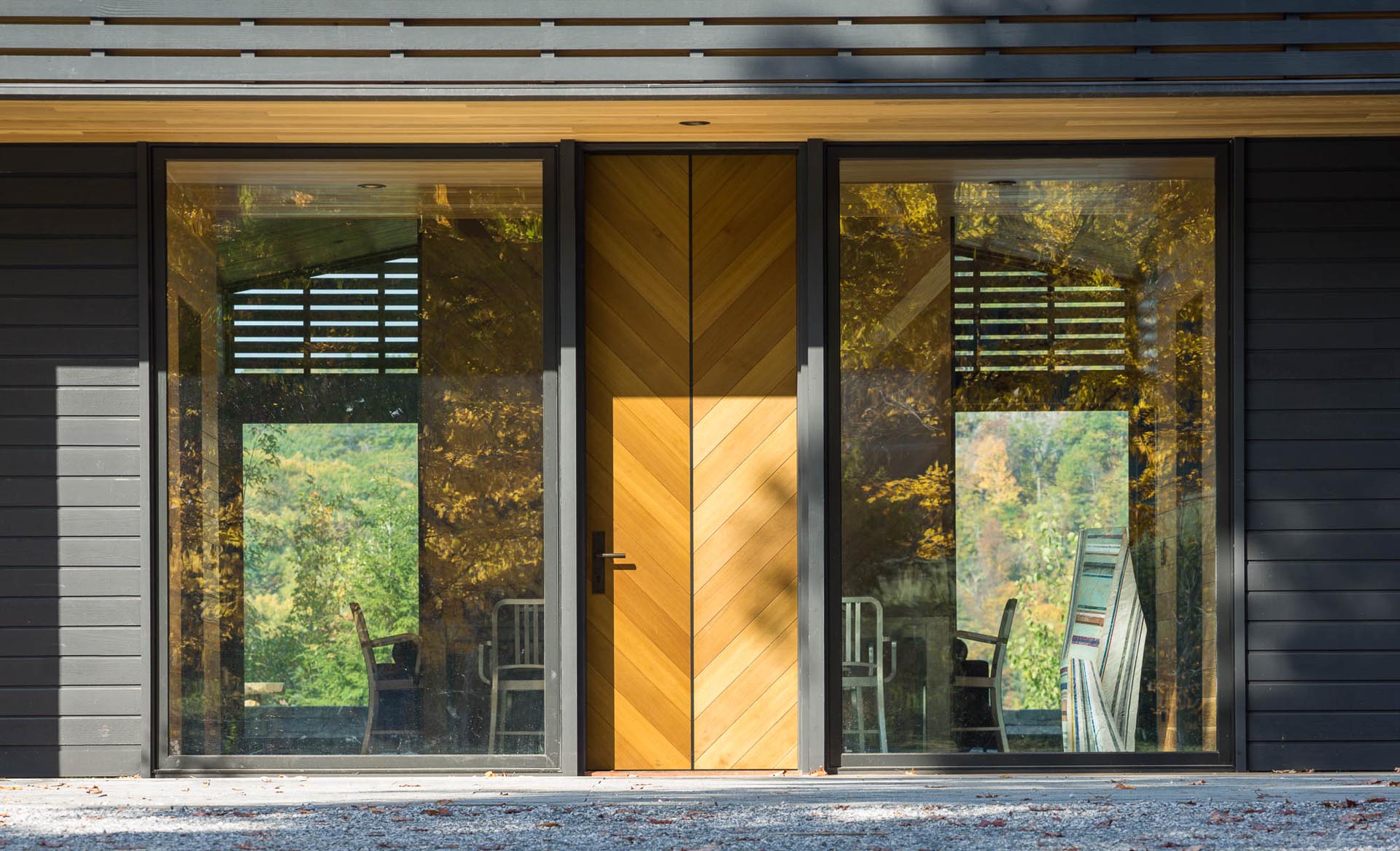 An oversized front door is flanked by two large floor-to-ceiling windows.