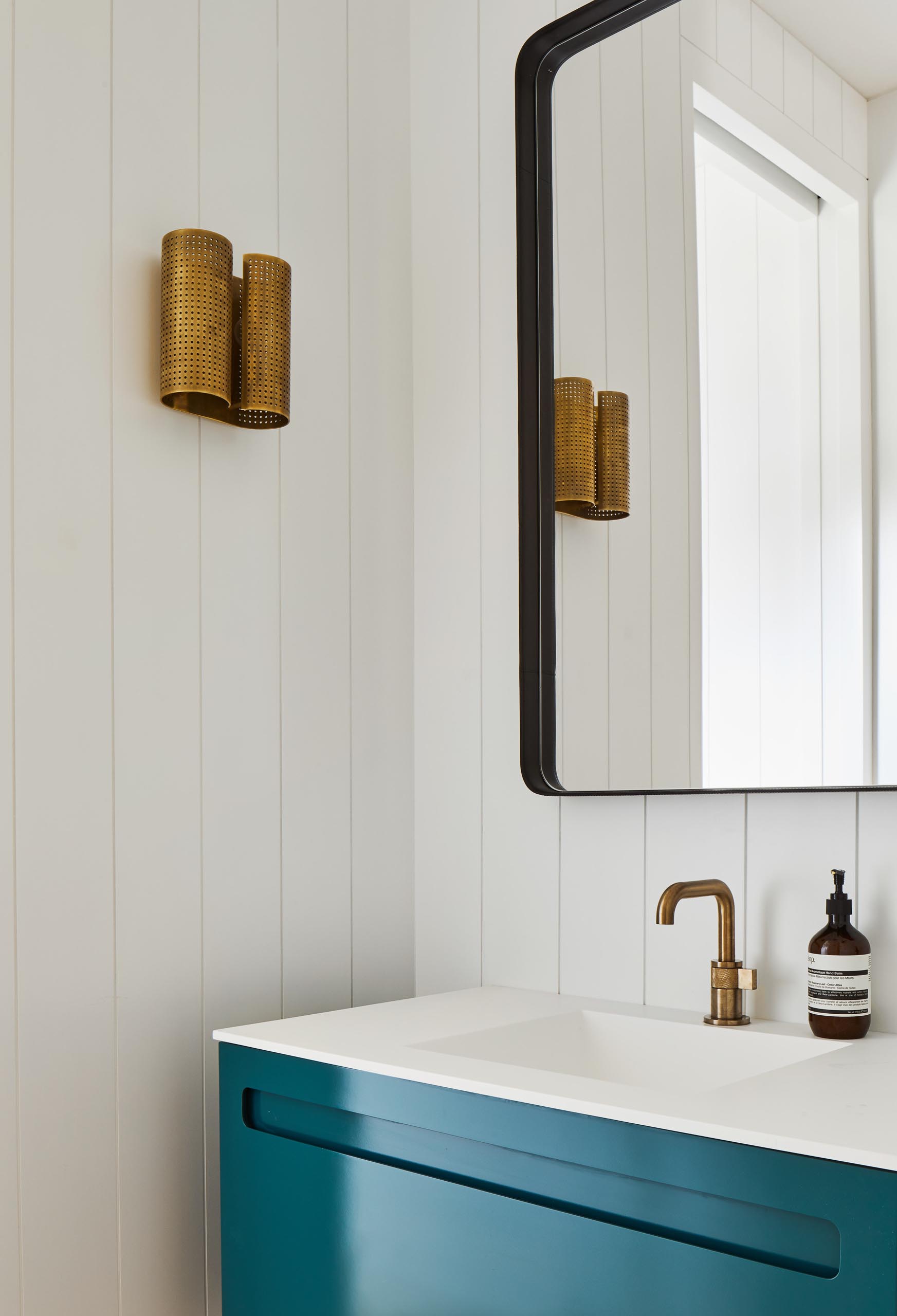 This powder room showcases a pop of color in the form of a bright blue vanity from A&F Supply in NYC, which is accented by Brizo faucet and a Kelly Wearstler sconce.