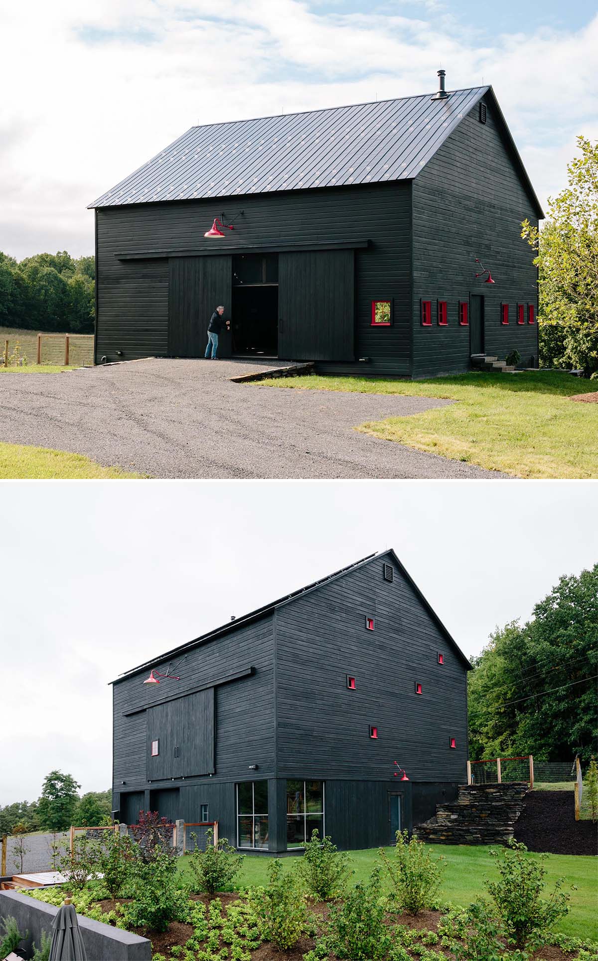 A modern black barn with solar panels and red window frames.