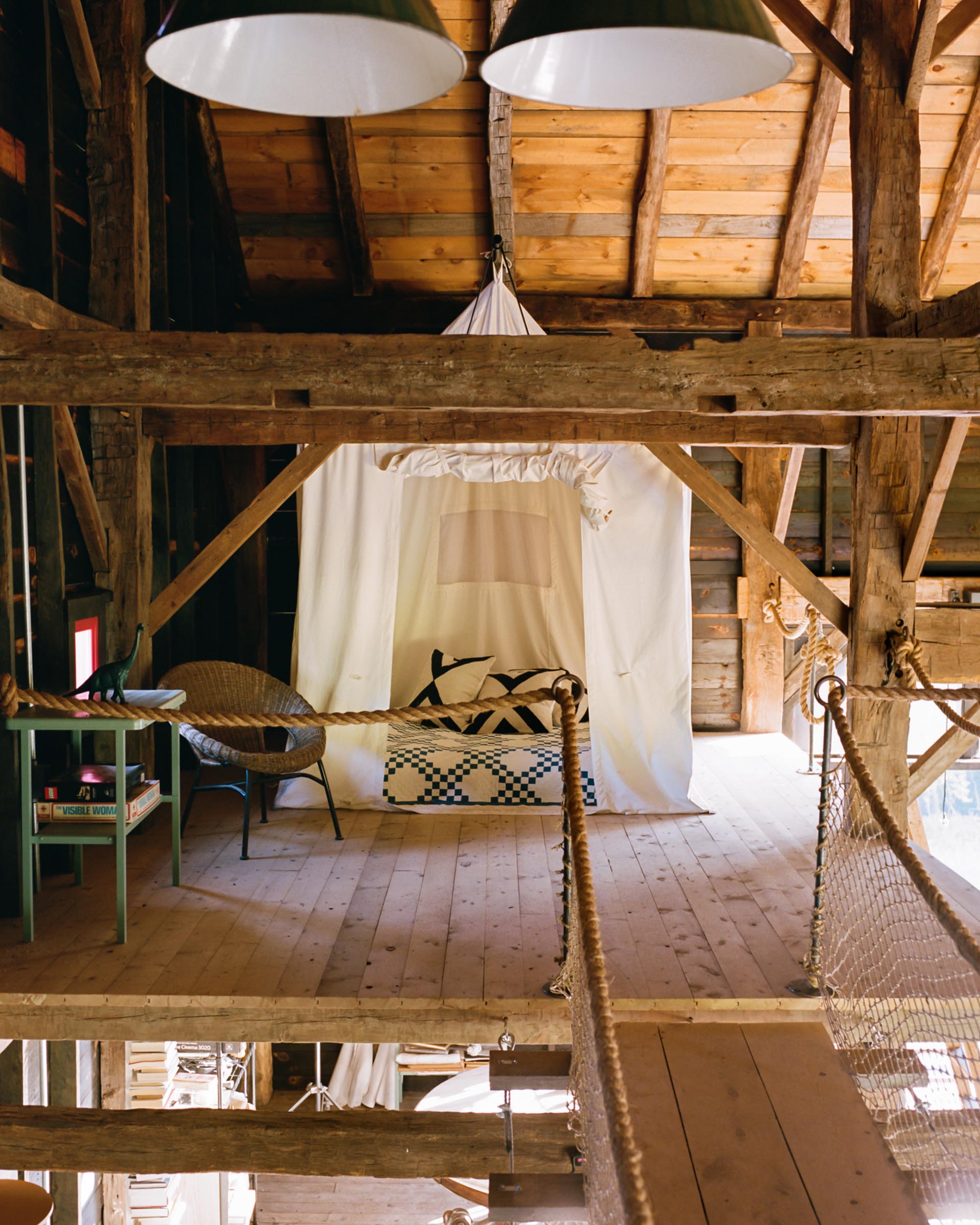 A barn interior with a bed surrounded by a fabric tent.