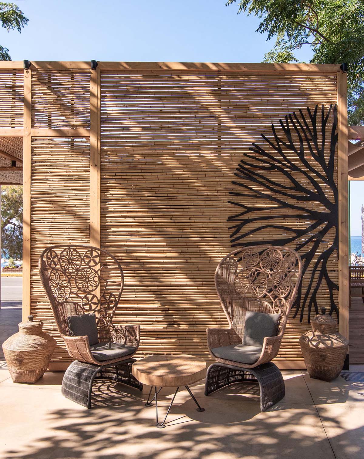 A modern outdoor restaurant with reed screens that provide shade and create a beach aesthetic.