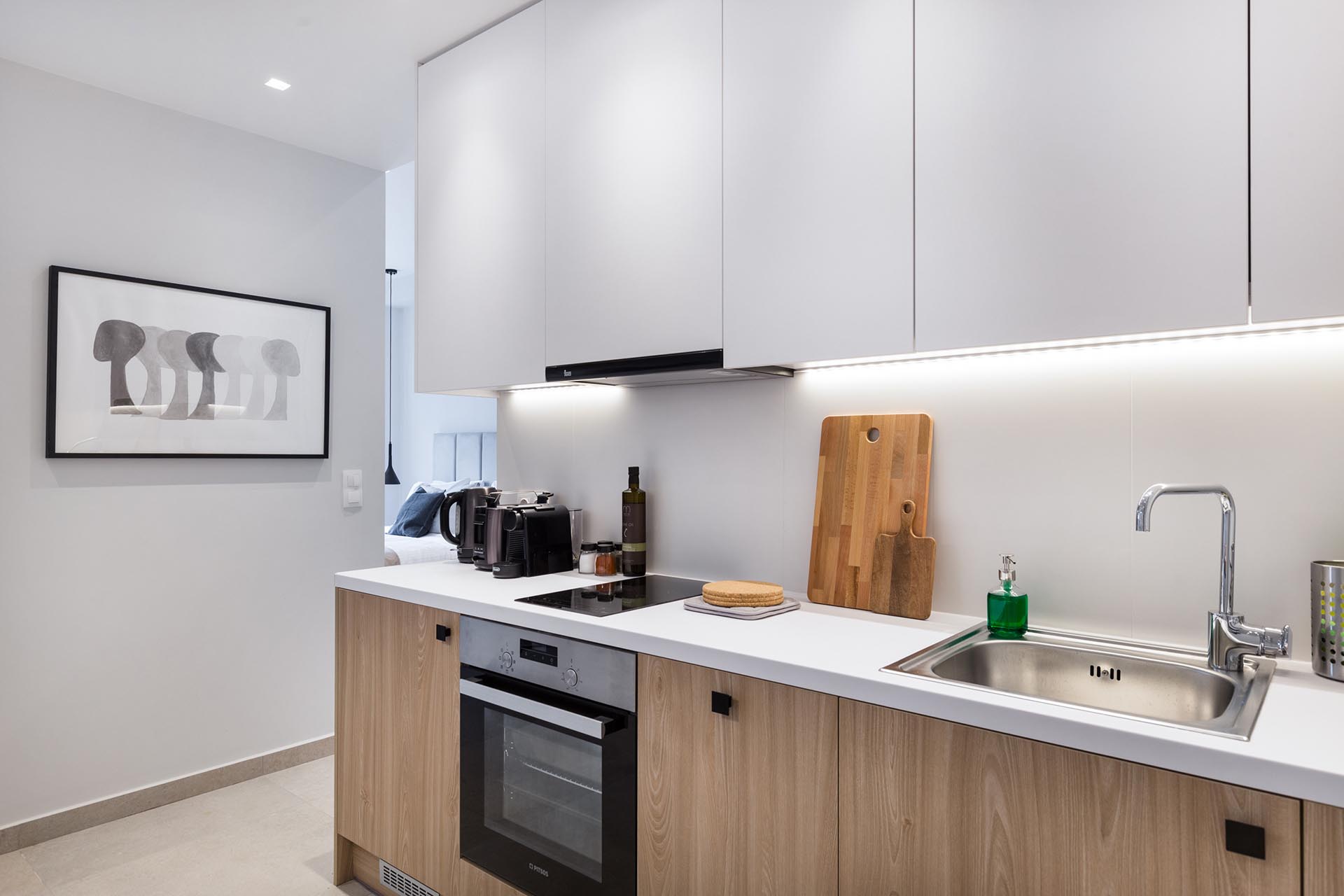 The modern kitchen of a small apartment includes undermount LED lighting.