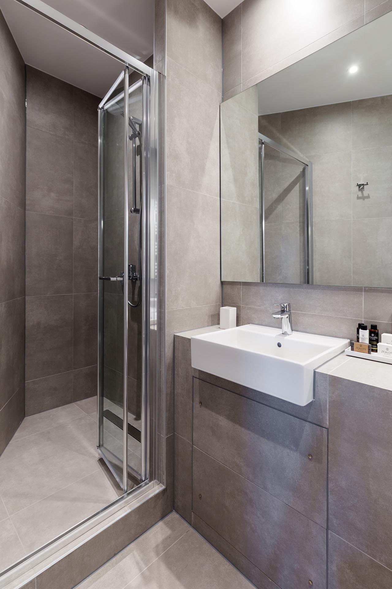 A small and modern bathroom with large format gray tiles.