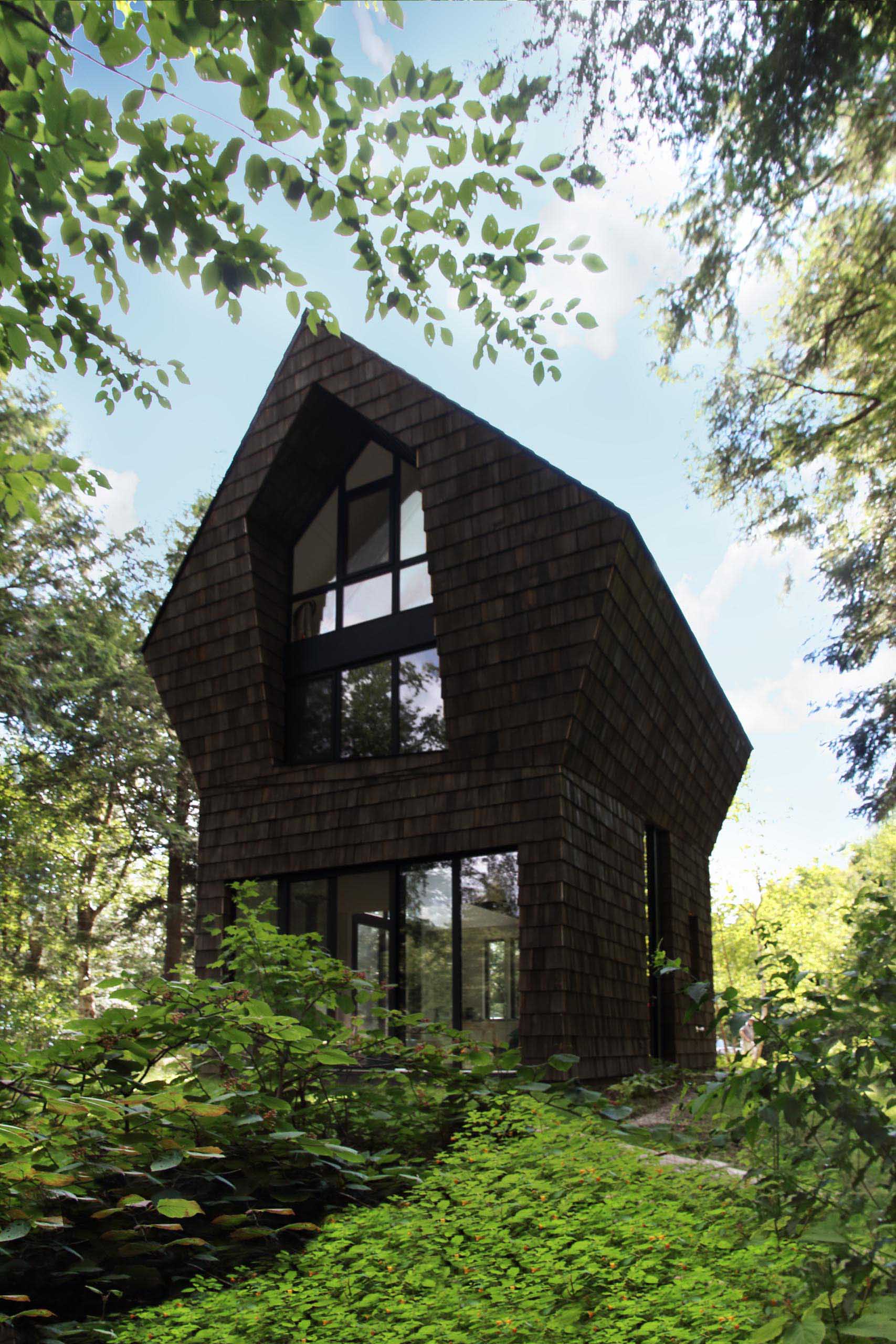 The dark cedar wood shingles of this cottage are complemented by black window and door frames throughout.