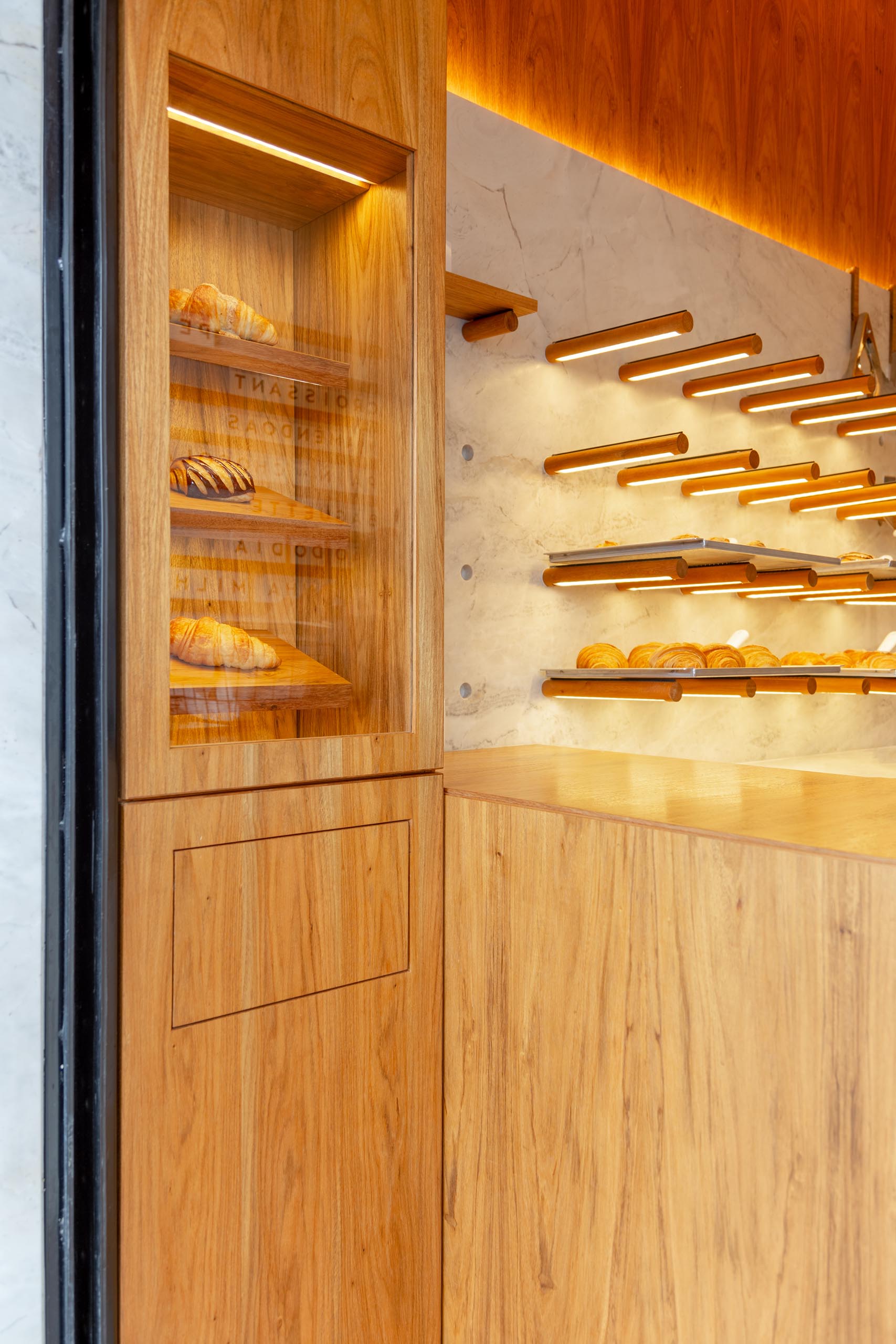 A small bakery makes use of wood dowels with hidden LED lighting to hold up shelving.