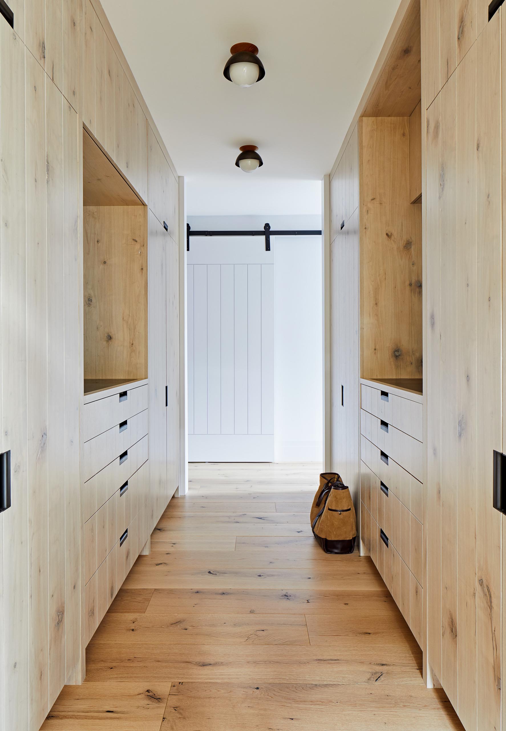 This master walk-in closet has plenty of space for storing clothes within the floor-to-ceiling wood cabinets.