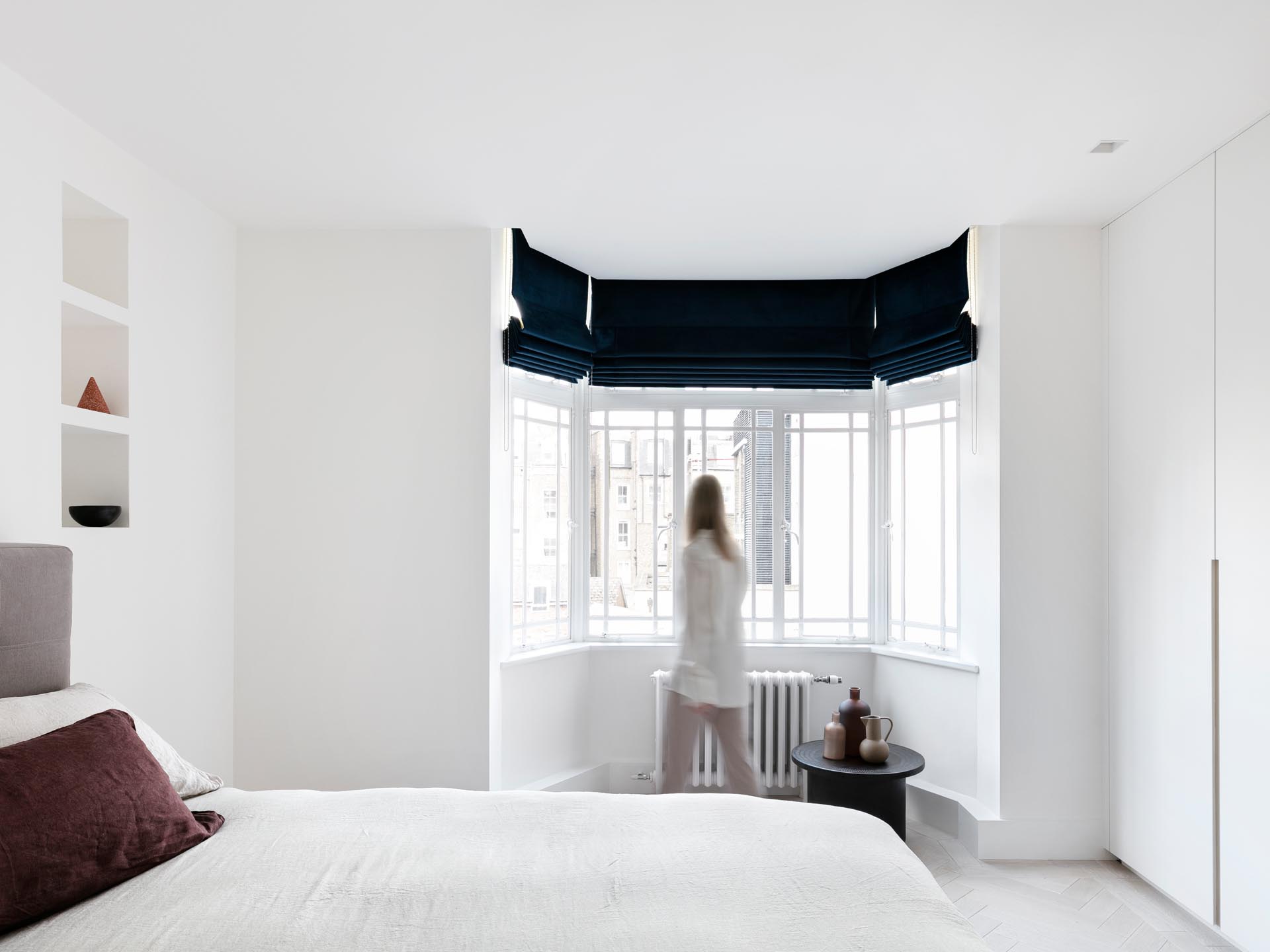 In this remodeled bedroom, the designers opened-up hidden wall niches, lowered the ceilings to hide curtain tracks, and created bespoke wardrobes.