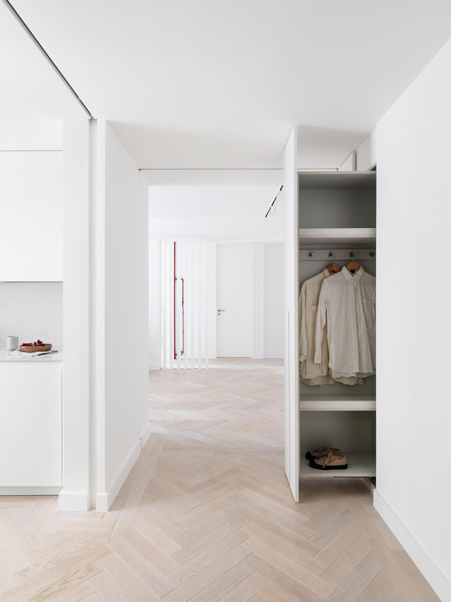 This modern entry hallway has a wall of cabinets that can be pulled out to reveal coat hangers and shoe storage.