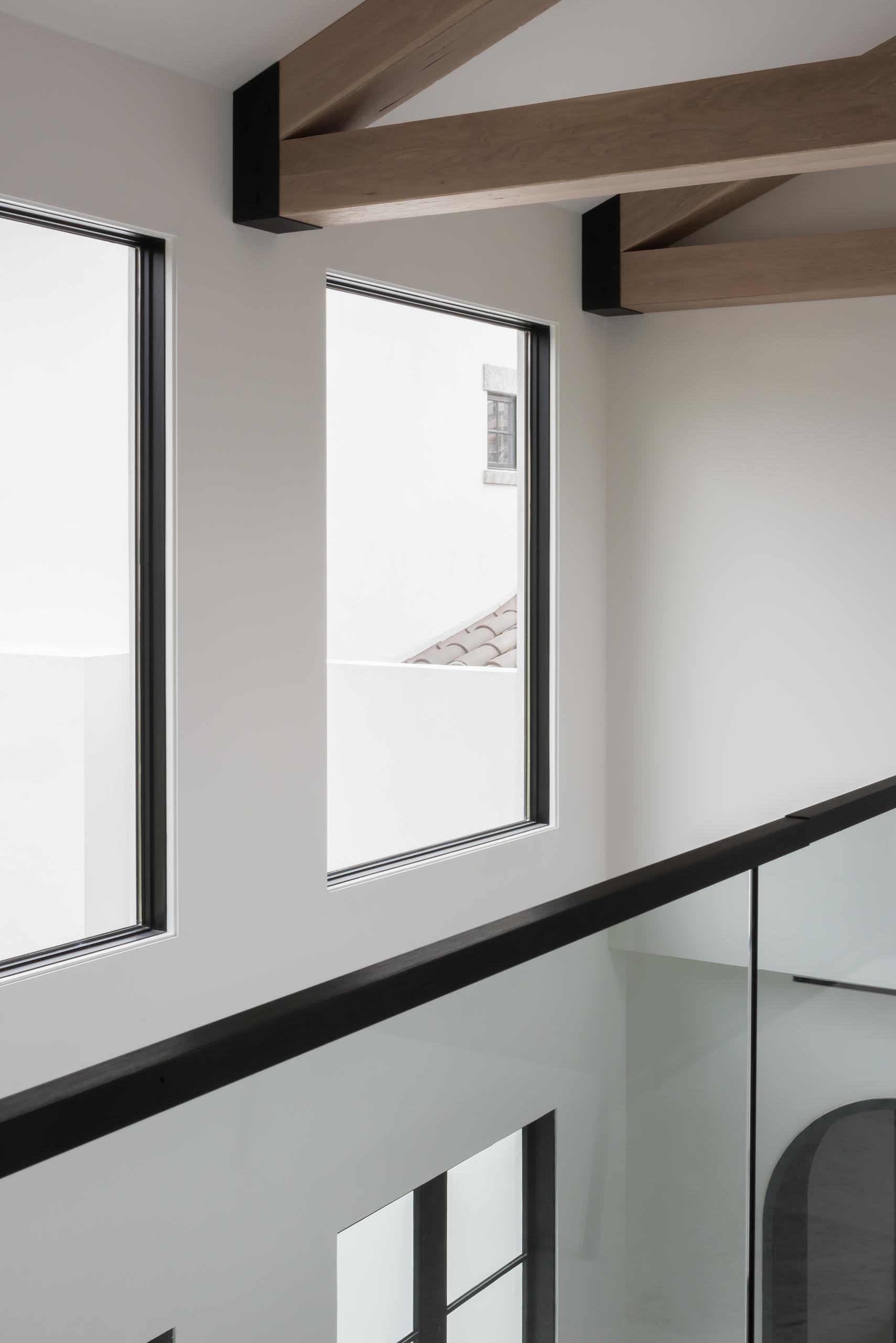 A modern interior with exposed wood trusses and black window frames.