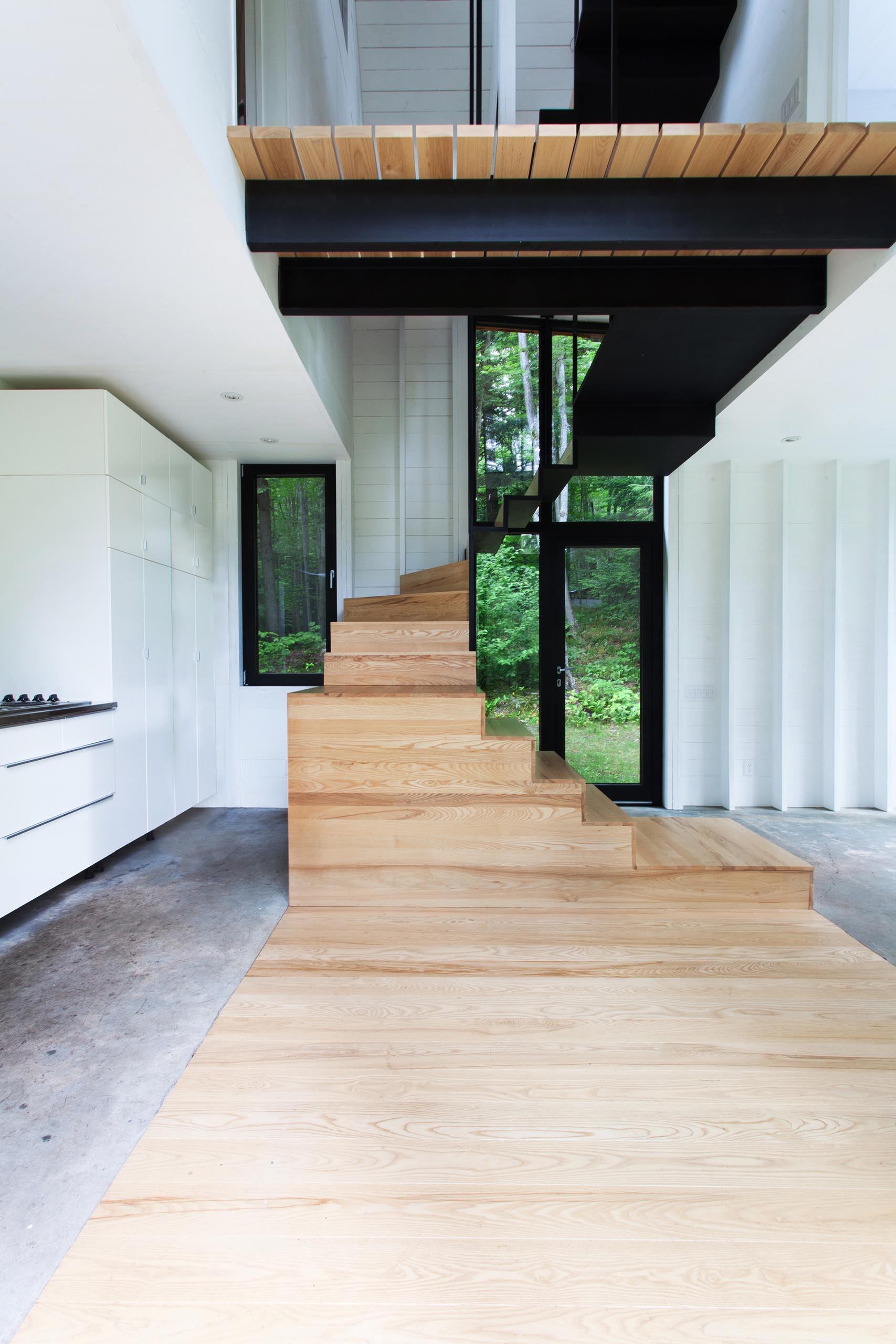 A small cottage with wood and concrete floors, and black window and door frames.