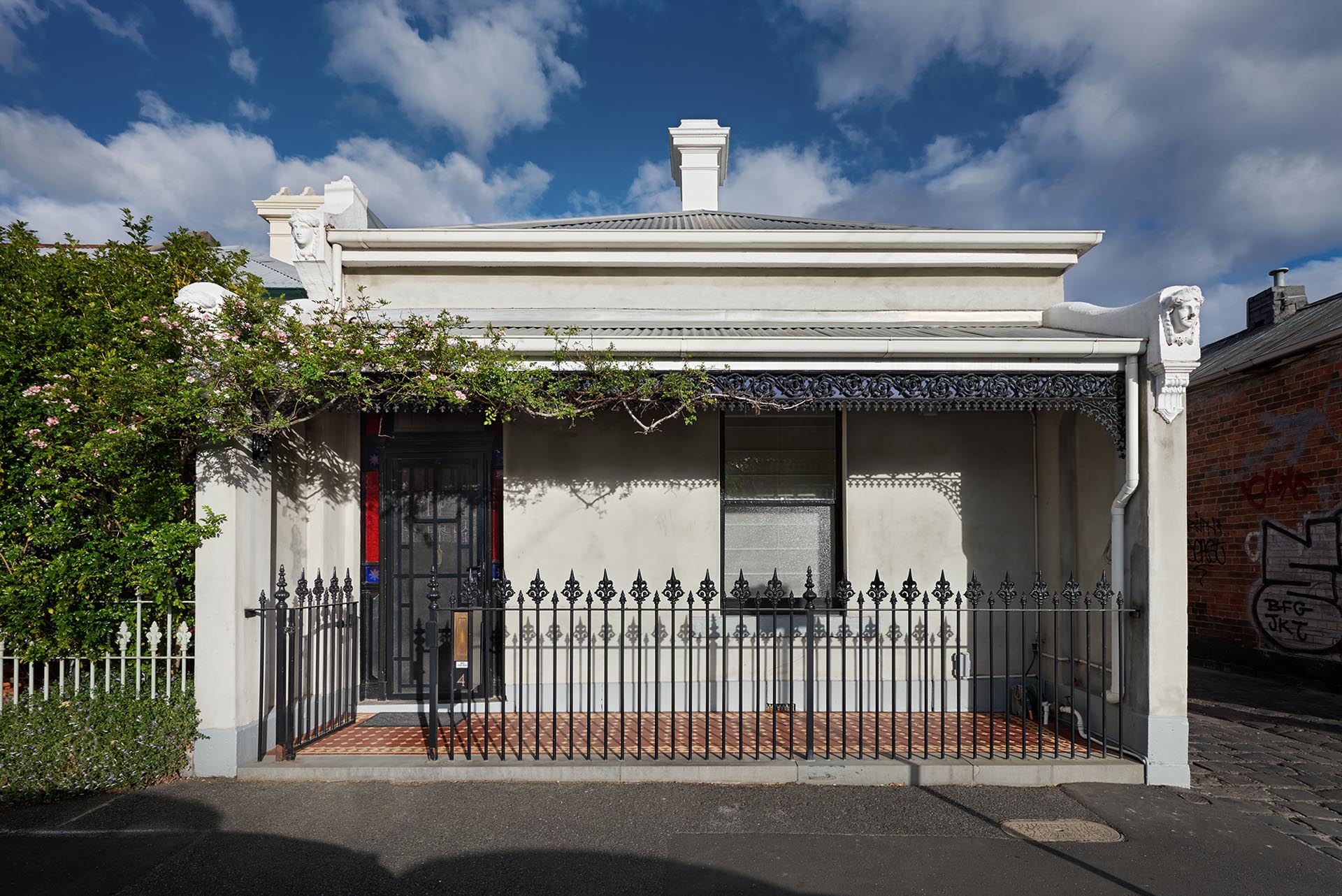 The home, located in Melbourne, Australia, has a traditional facade that includes ornate iron work and a small front porch.