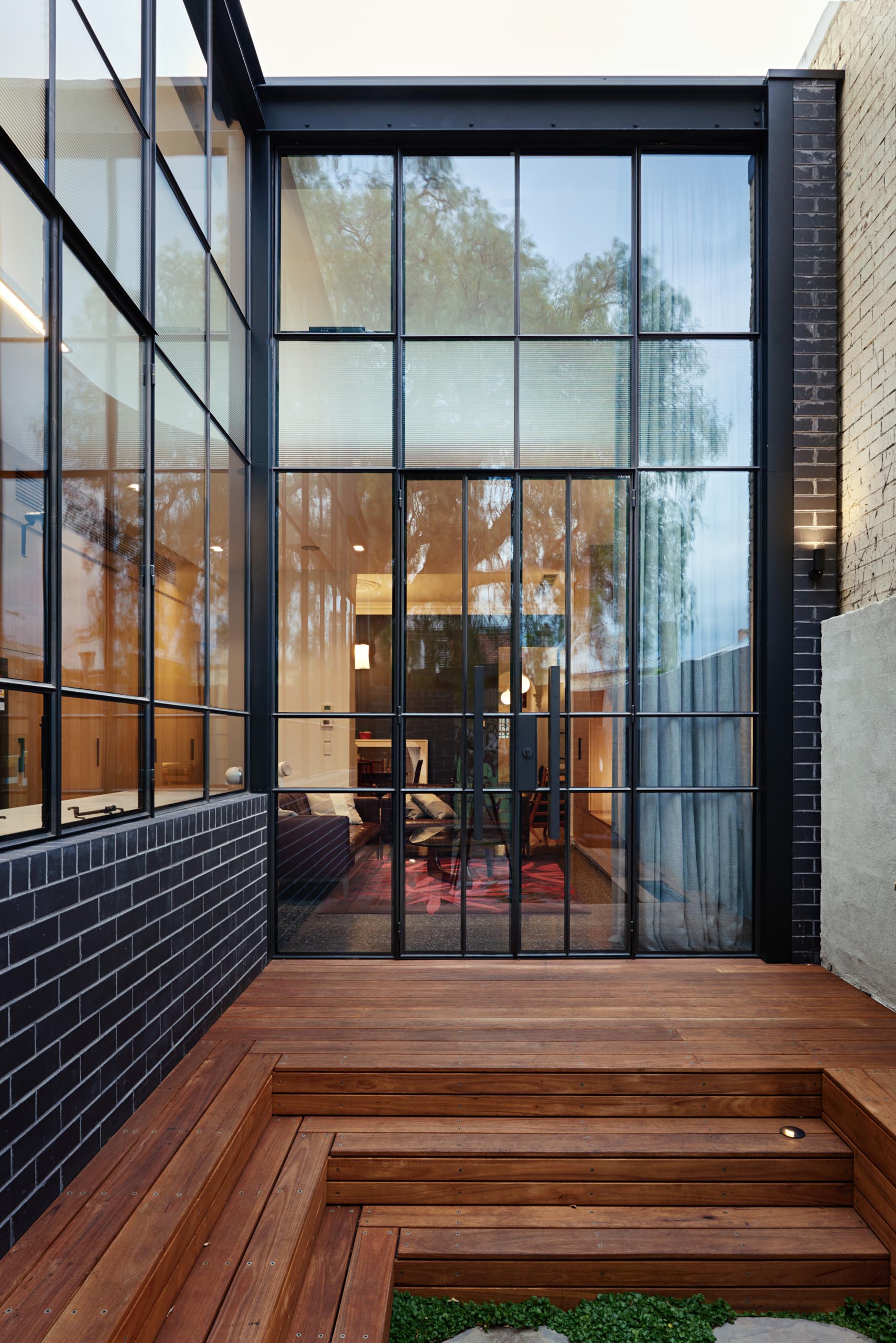 A modern house extension that includes black brick and a black framed glass wall.