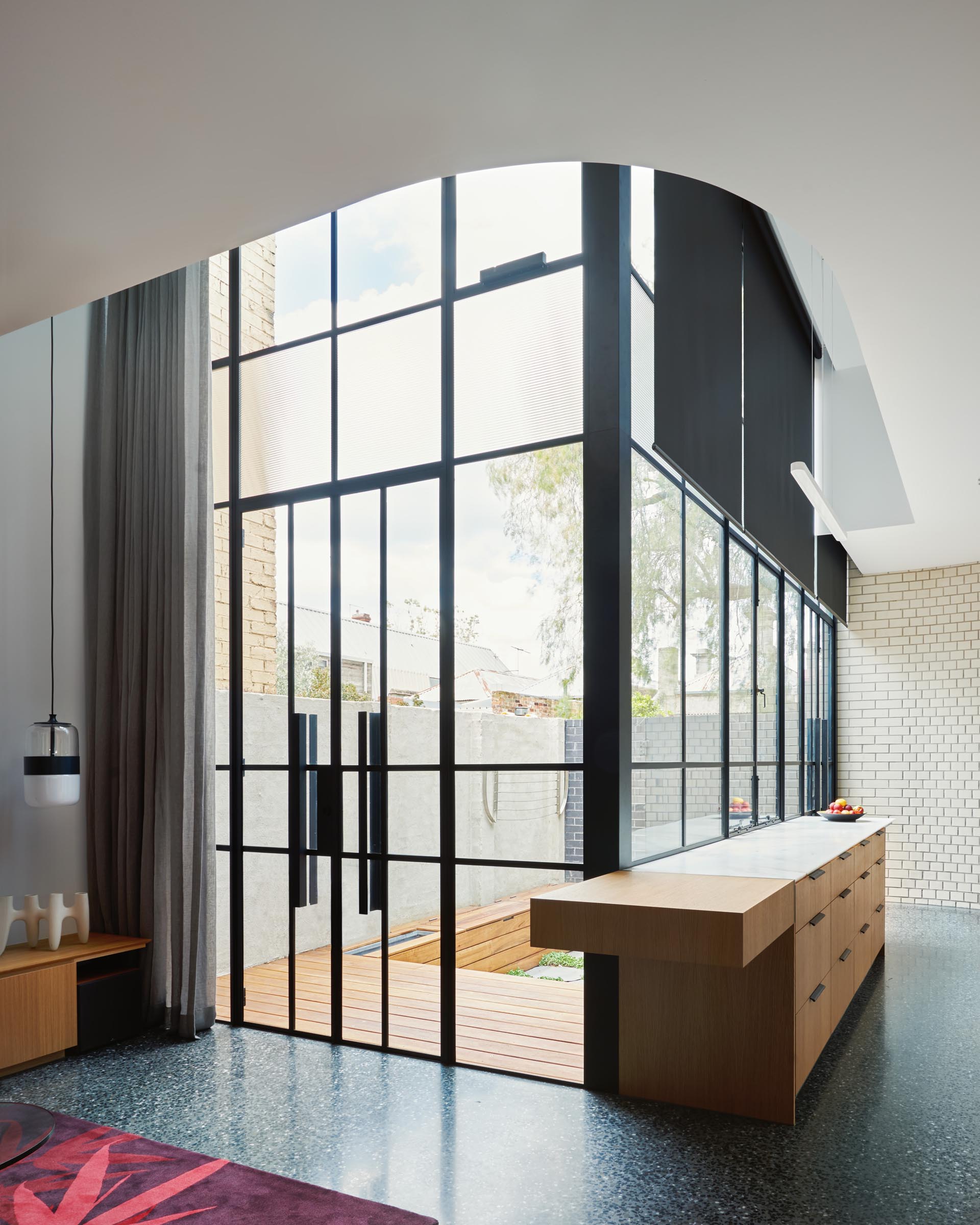 Black framed glass doors which blend into the glass walls, help to create an abundance of natural light that filters through to the interior.