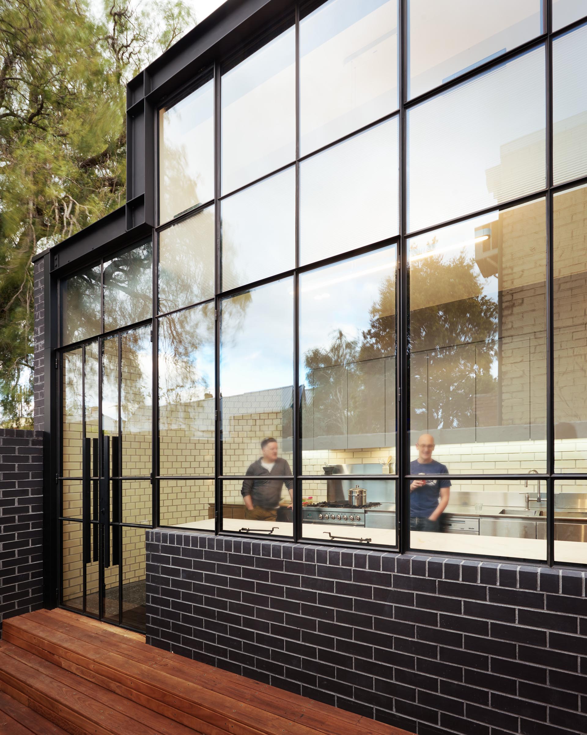 A modern house extension that includes black brick and a black framed glass wall.