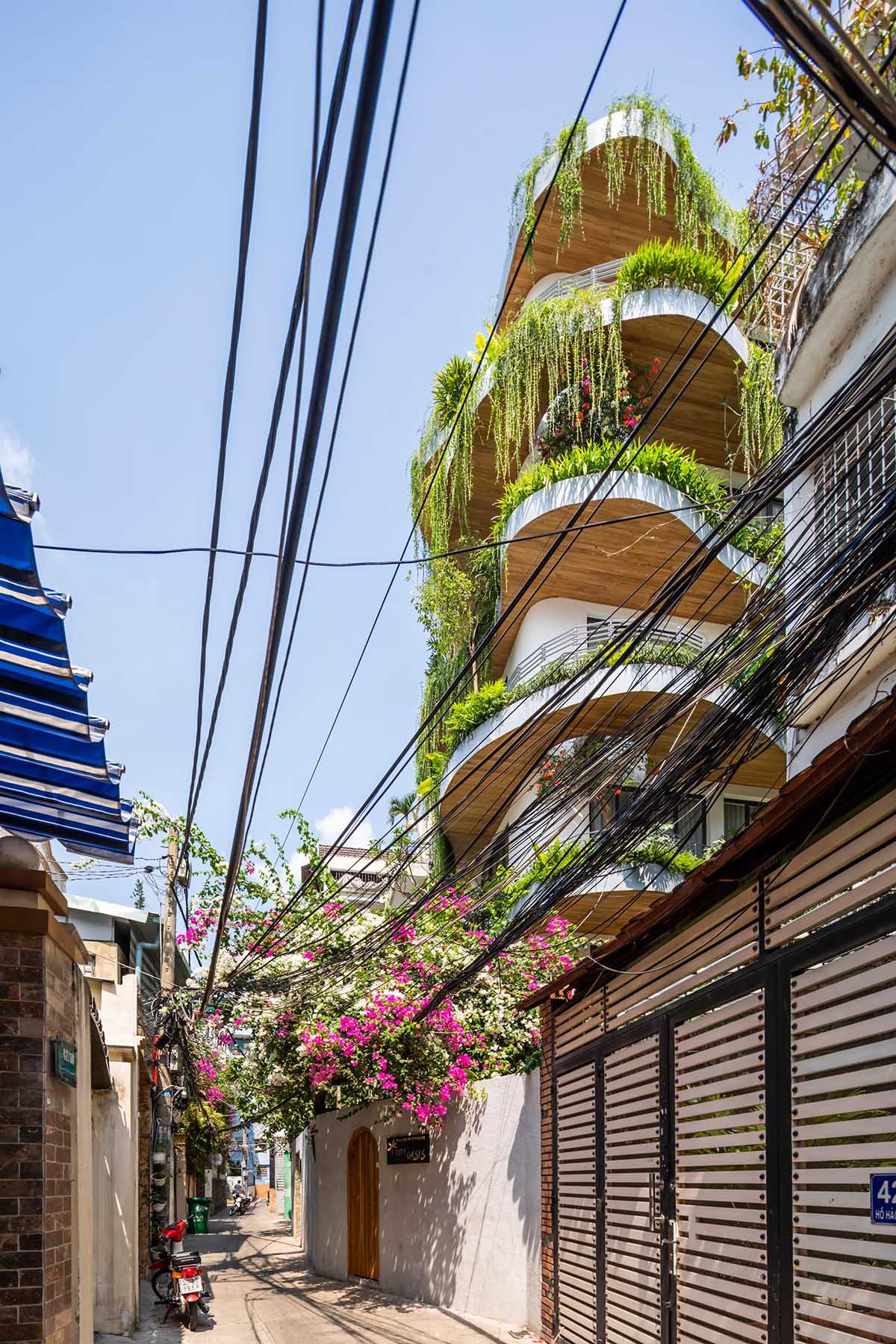 A modern building with curved balconies and overhanging plants.