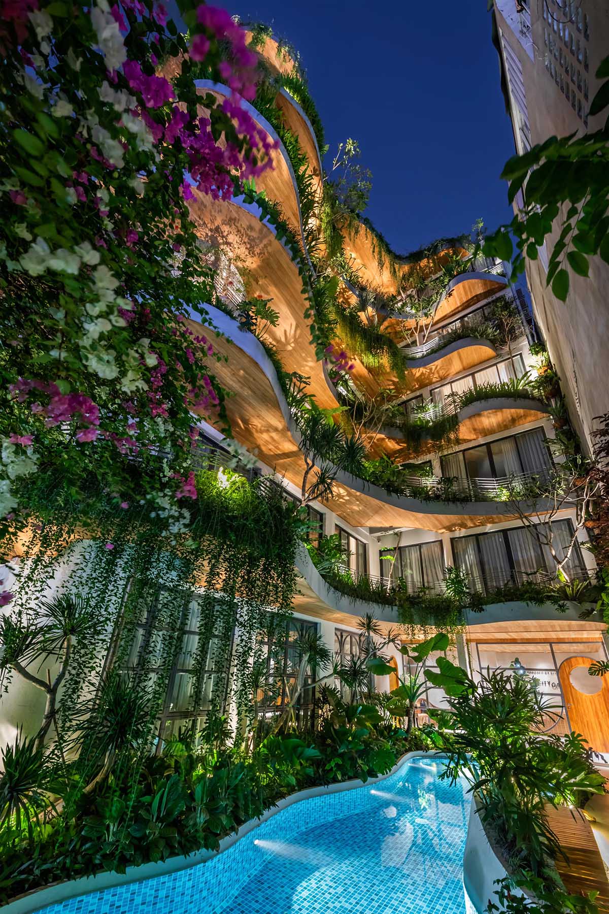 A modern building with curved balconies and overhanging plants.