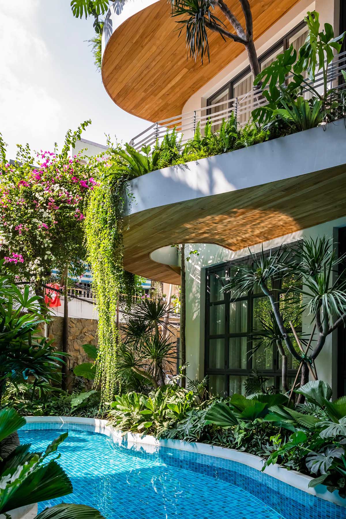 A modern building with curved balconies and overhanging plants.