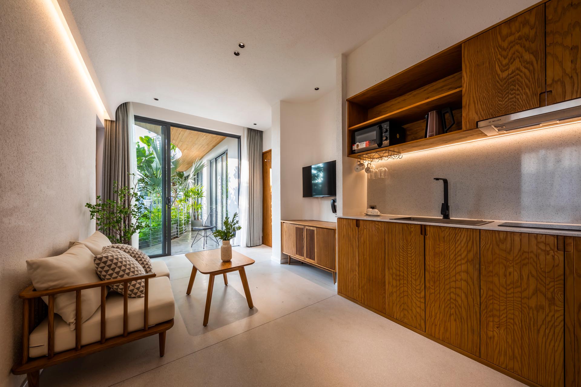 A minimalist apartment interior with LED lighting, a small living room, and kitchenette.