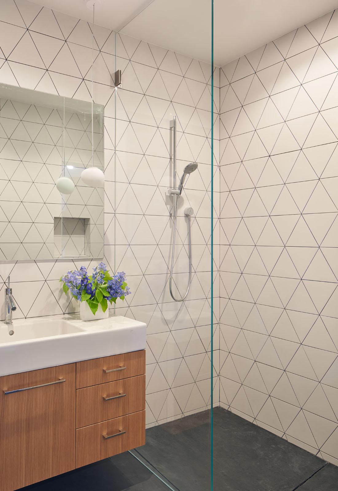 In this modern bathroom, triangular tiles cover the walls with the dark grout used to highlight the design.