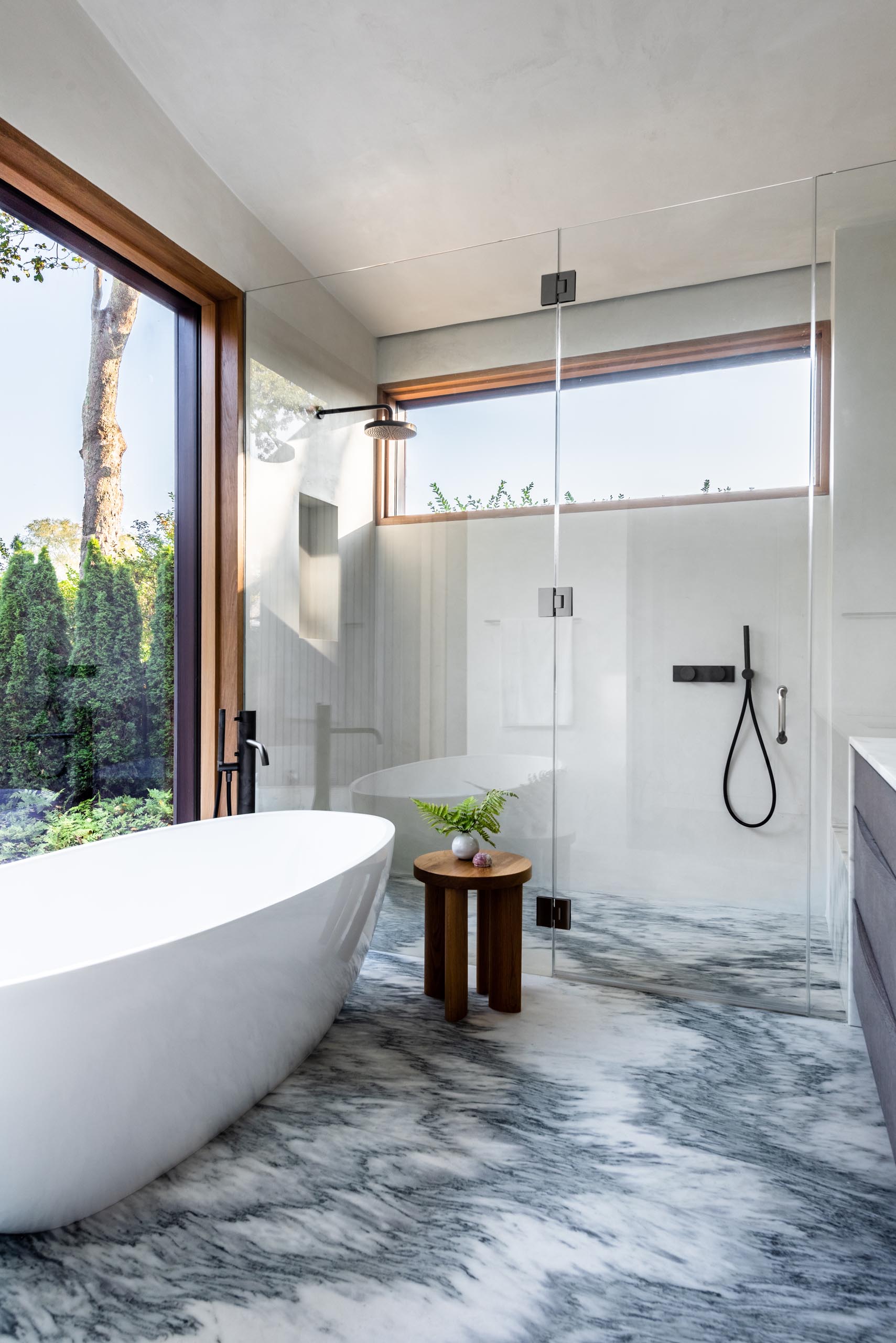 In this modern bathroom, an eye-catching floor complements the white freestanding bathtub and black bathroom hardware.