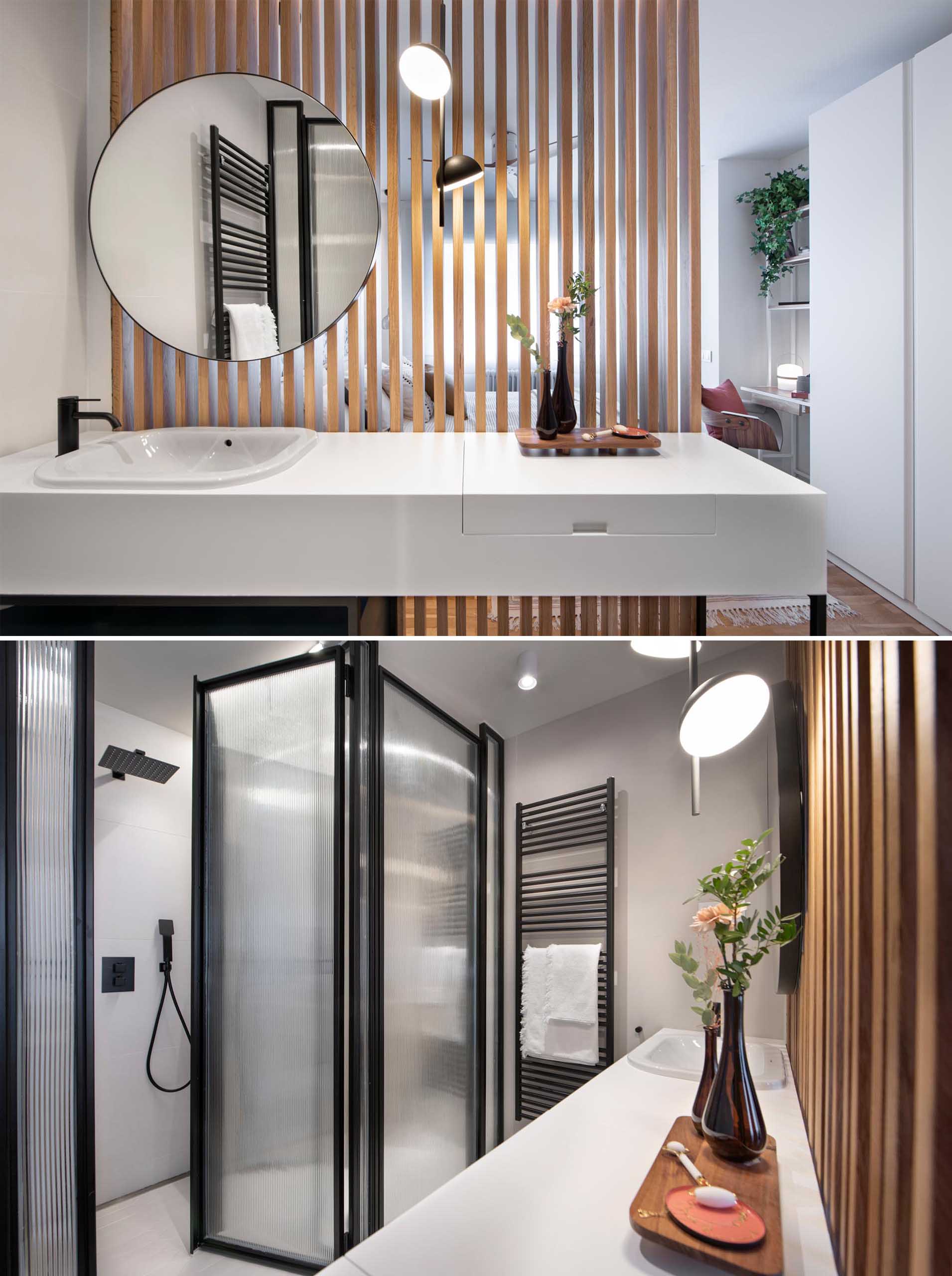 This en-suite bathroom is separated from the bedroom by a wood slat wall, while black framed glass walls hide the shower and toilet, and the vanity has a thick white countertop that hides a makeup area.