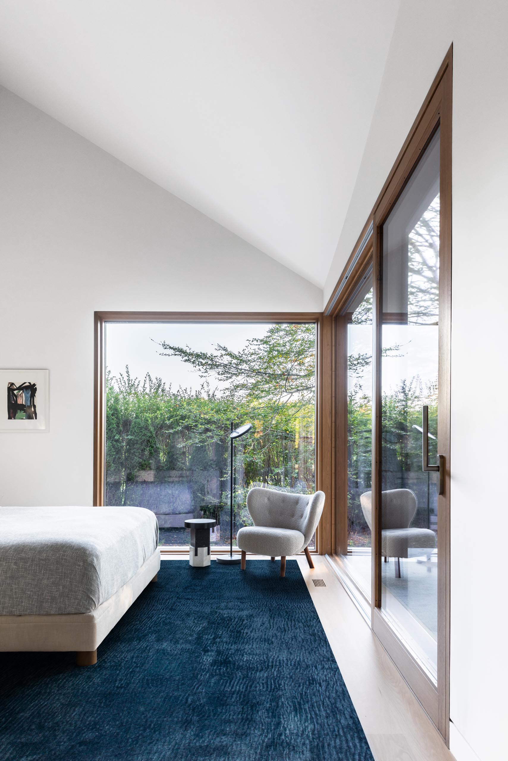 In this modern bedroom, large windows with wood frames provide views of the garden.