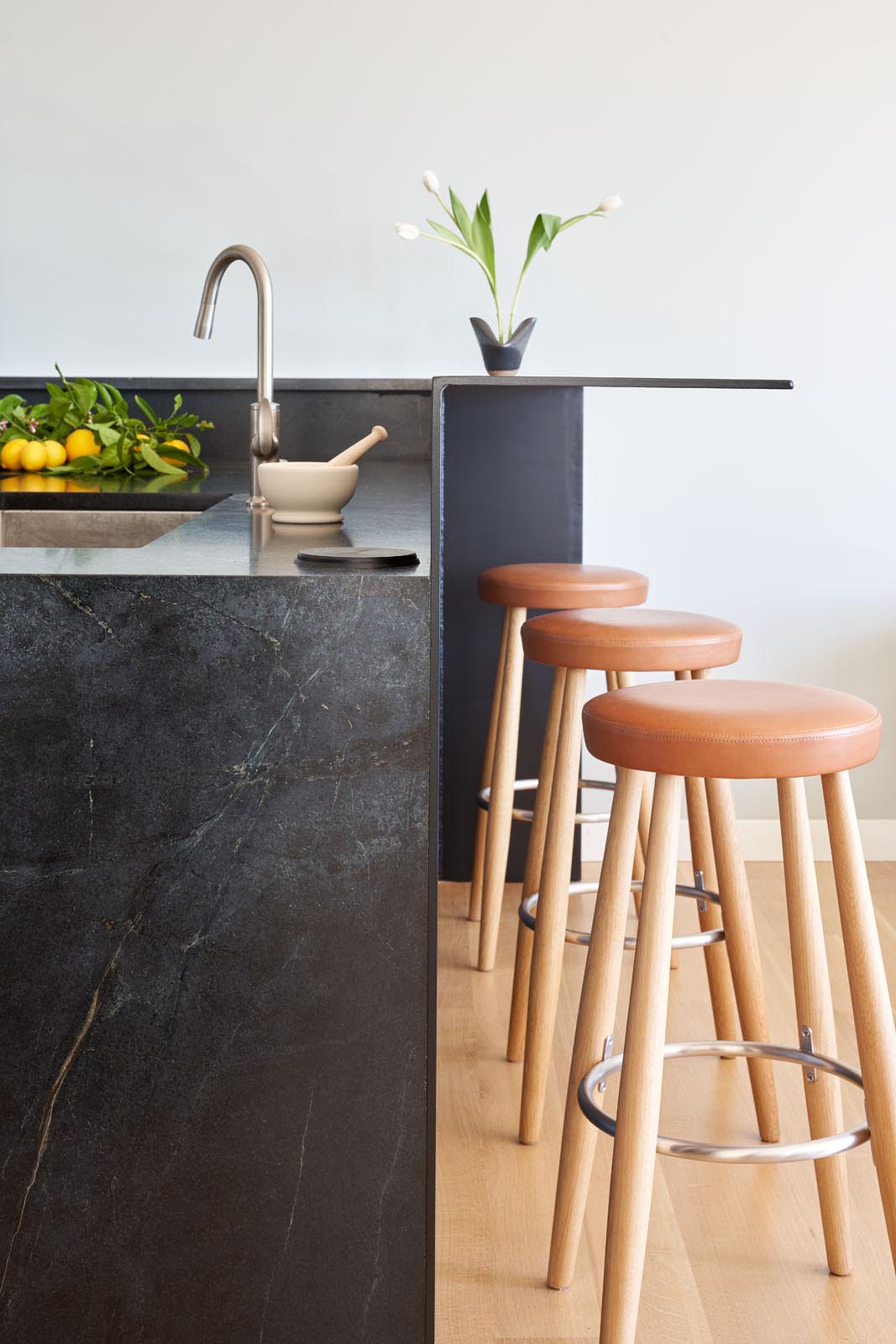 This modern kitchen has dark countertops that connect with a raised steel breakfast bar.