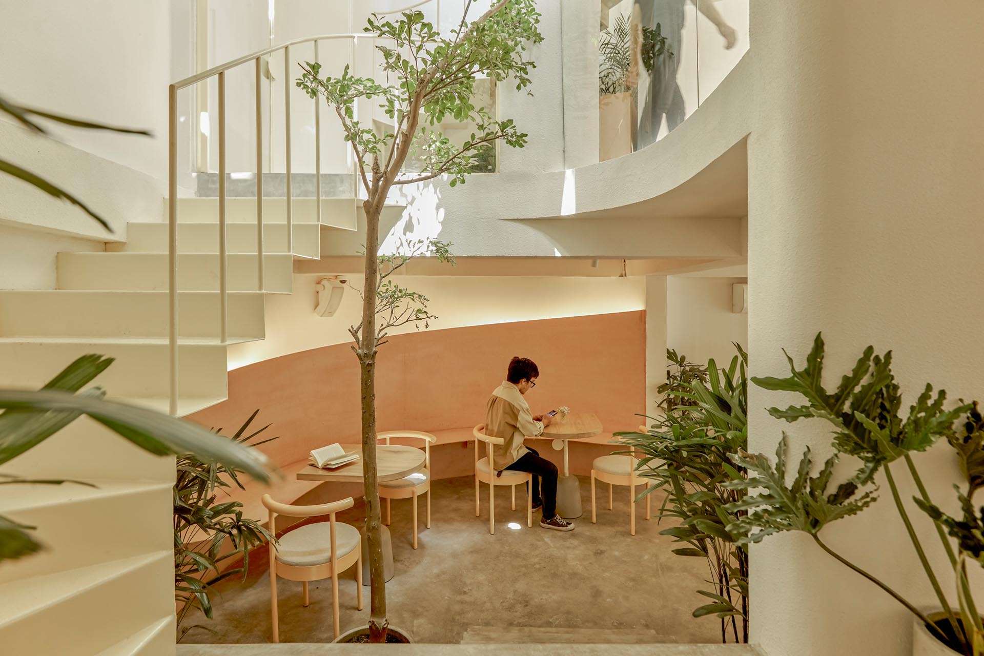 The interior of this modern coffee shop uses gentle neutral tones such as white, beige, rose-orange, and natural wood colors. 