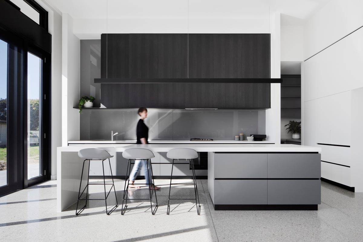 In the kitchen there's a large island with room for seating, and a minimalist linear pendant light hanging above.