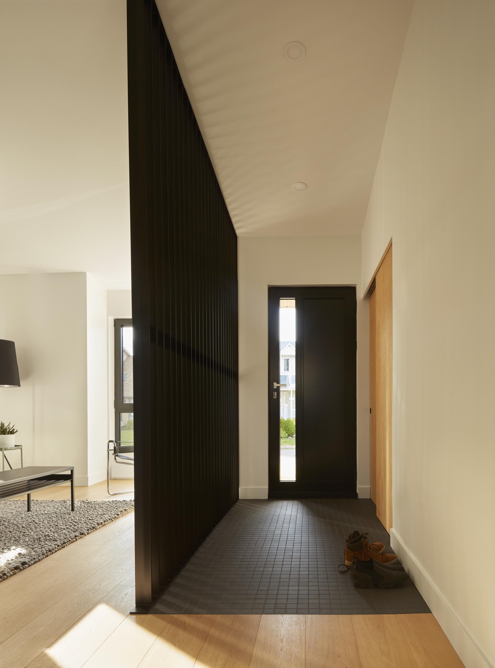 This modern room divider, which also complements the dark tiled floor, allows the light from the living room to travel through to the entryway.