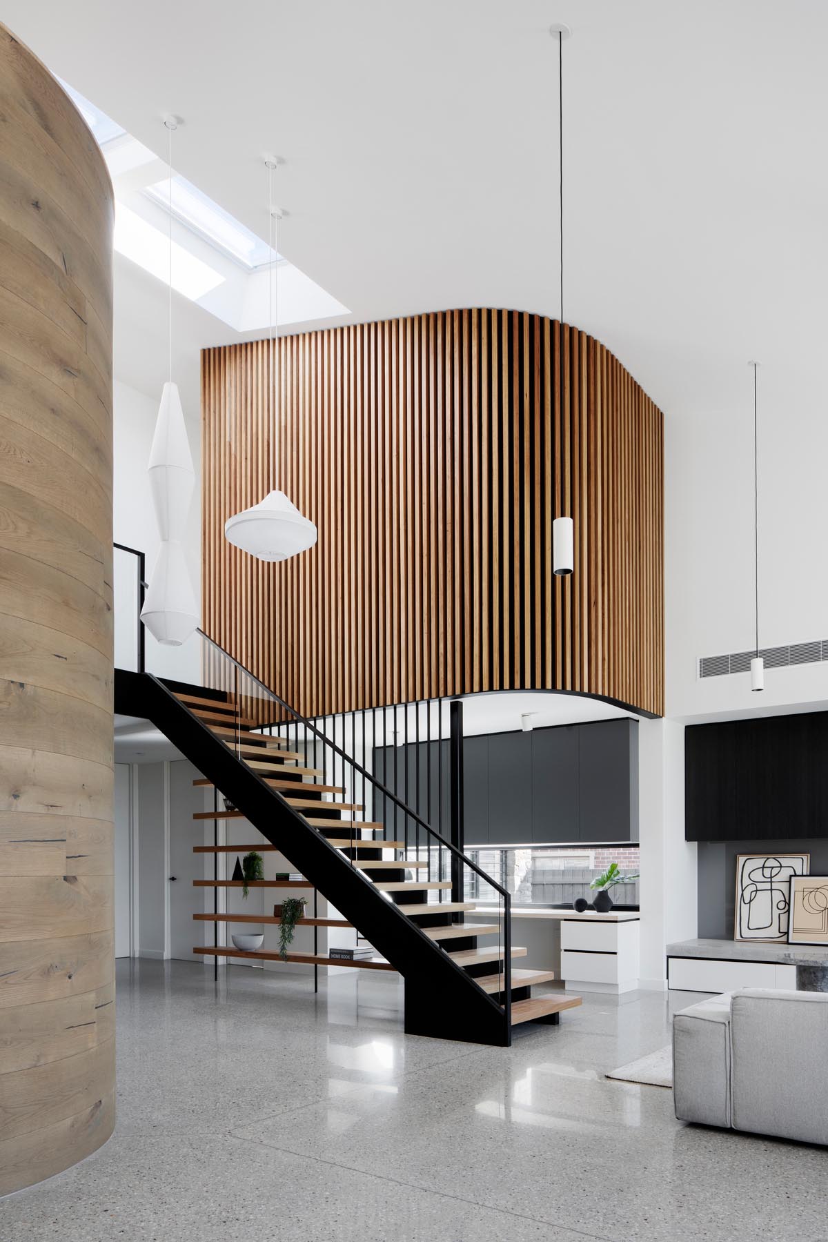 A modern interior with a curved timber wall and a second wood wall clad in timer battens.