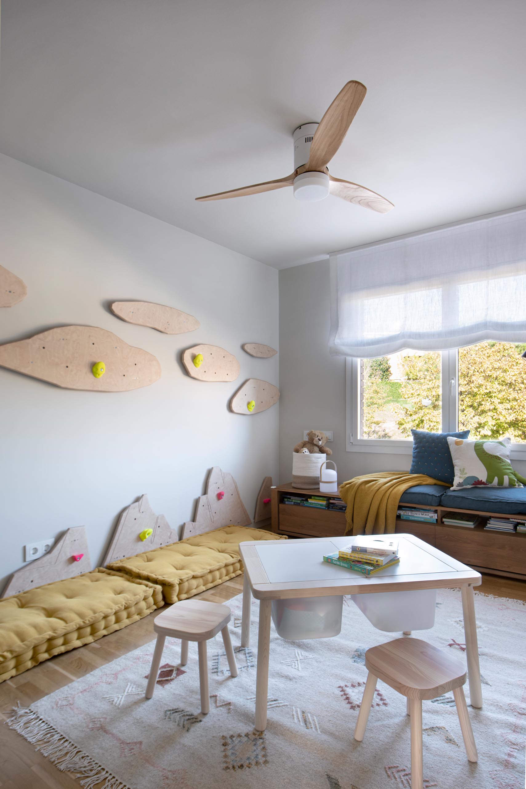 In this modern kid's bedroom, there's uniquely shaped wood cut-outs on the wall that have been designed to attach rock climbing mounts, turning the one empty wall into a climbing wall.