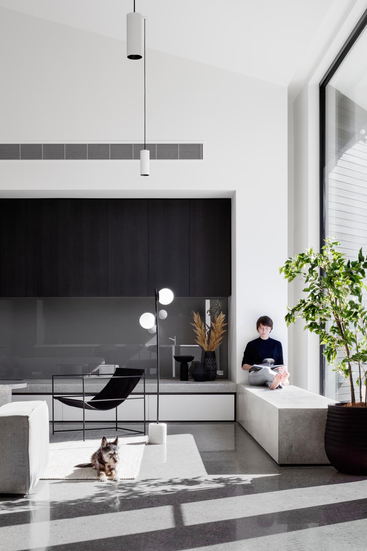 This modern living room has a minimalist fireplace and a concrete window bench by a large window.