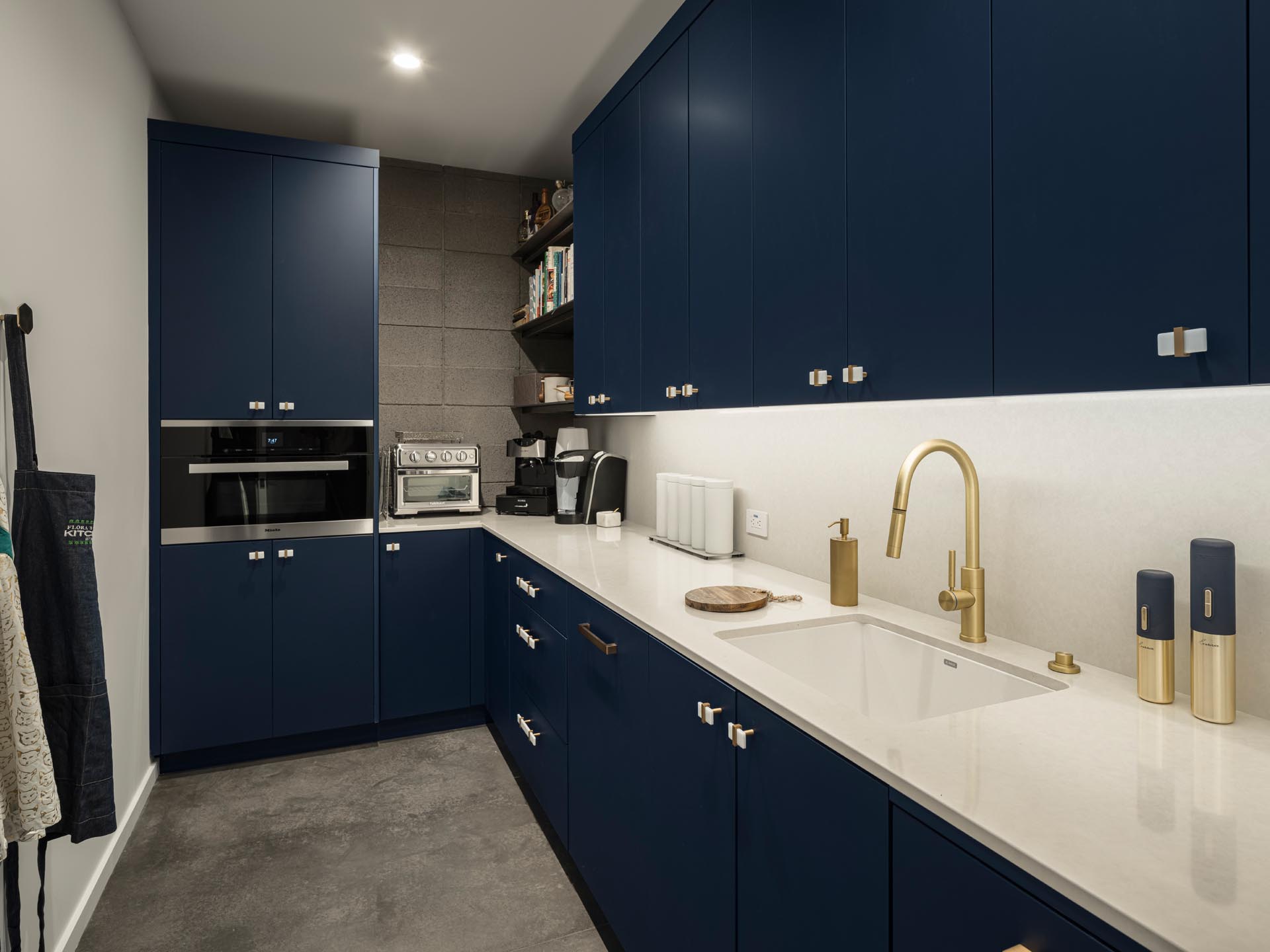 A large walk-in pantry with dark blue minimalist cabinets, that provide plenty of storage room.