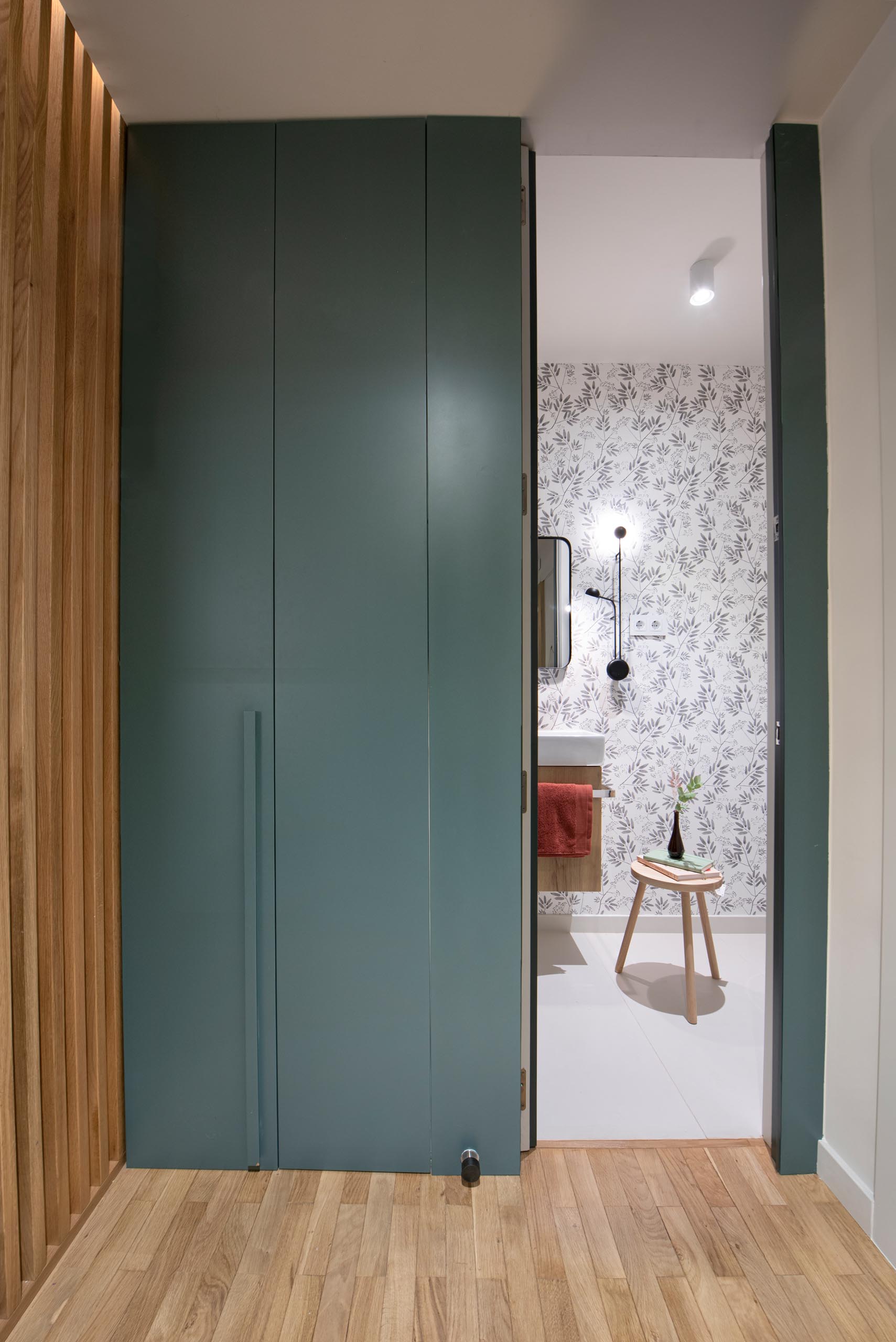 This modern home includes a three-door wardrobe in a eucalyptus green finish, that hides a minimal, functional and attractive powder room