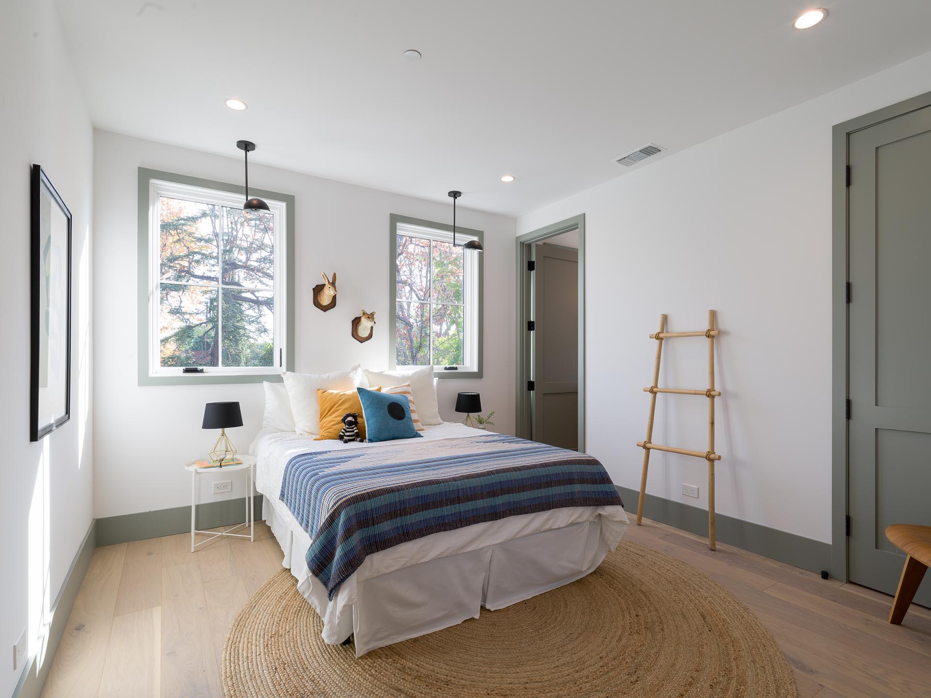 A contemporary bedroom with white walls, wood floors, and gray trim.