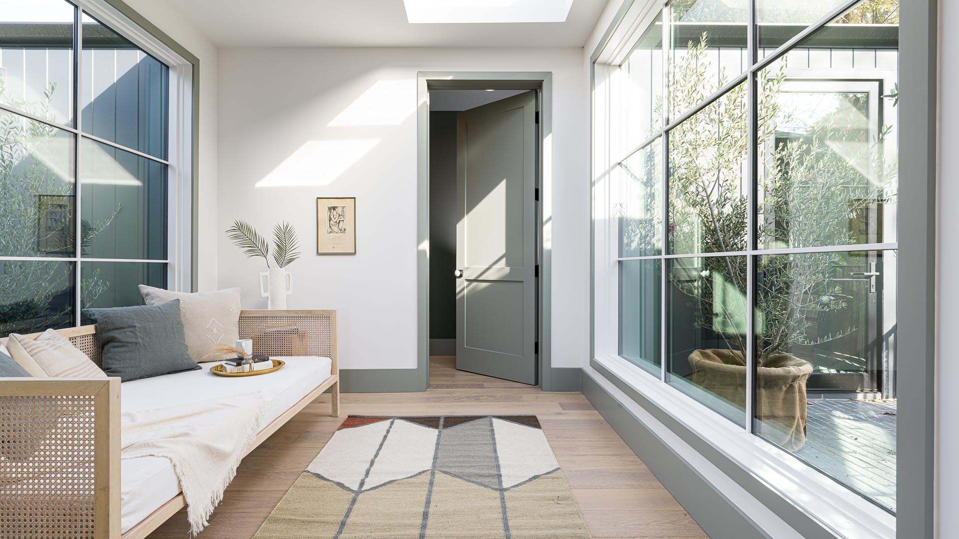 A sunroom with wood flooring, and walls of windows on either side.