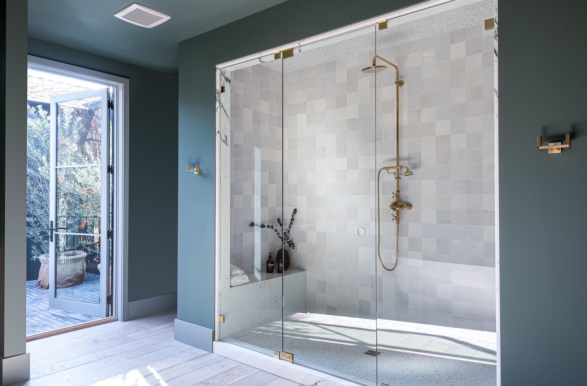 The glass enclosed walk-in shower is lined with square tiles, while a bench has been built-in at one end.