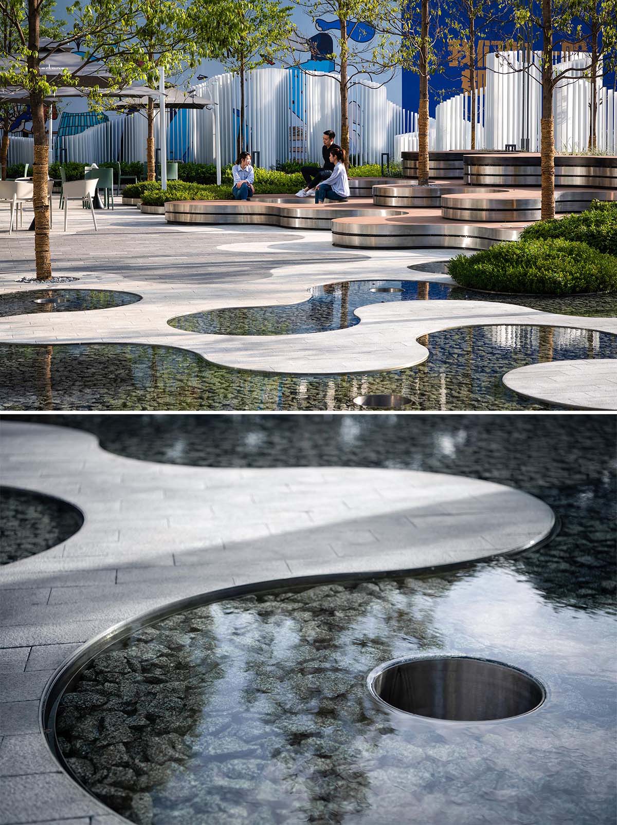 A landscaped park that includes curved tiered seating, water features, and a vertical white strip fence.